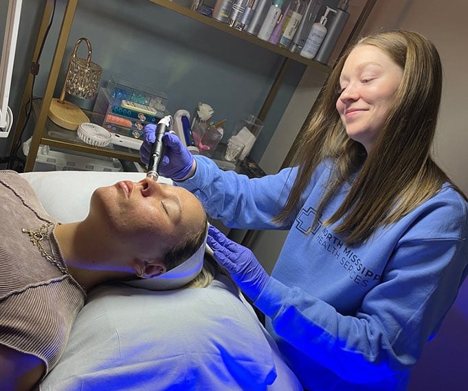 Esthetician performing a med spa service on a female client's face