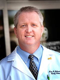 photo of Dr. Kevin Johnson smiling outside the clinic in a white lab coat