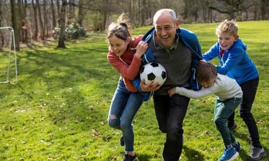 grandfather playing soccer with grandchildren