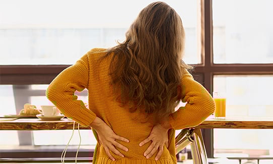 back view of a young woman holding her back in pain