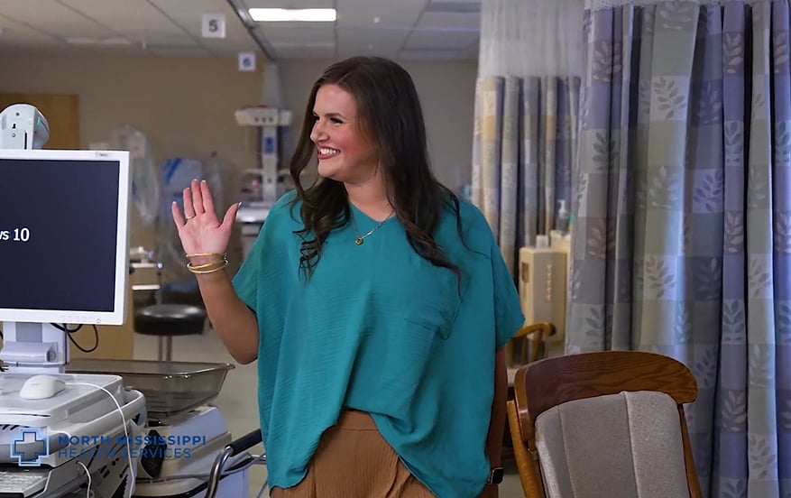 Jala Marchbanks walking through the hospital, waving and smiling at a coworker. 