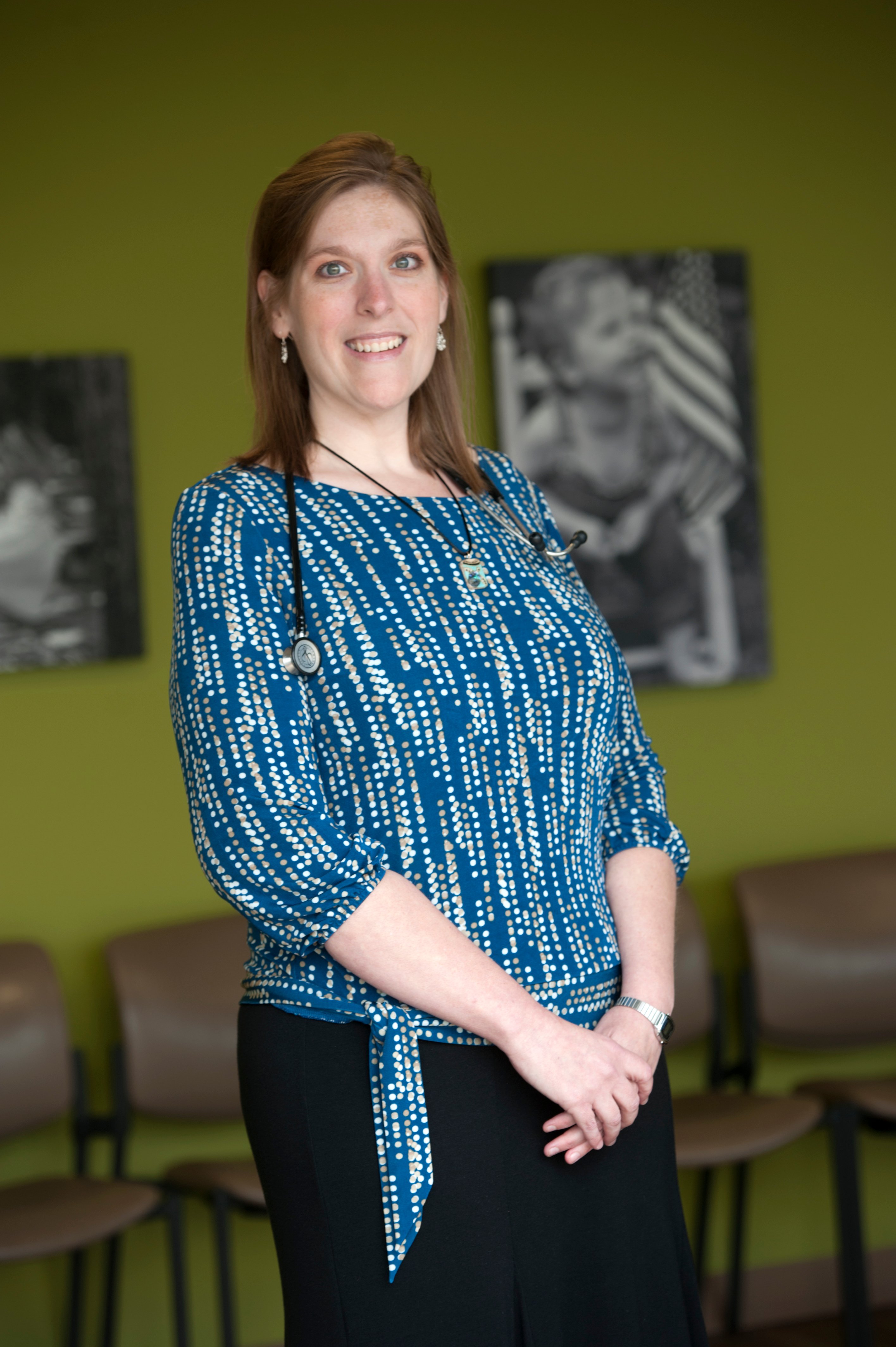 Dr. Nikki Ivancic smiling in a clinic lobby with a green wall behind her.