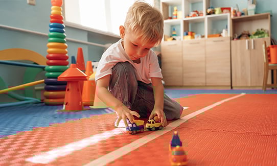 young child playing with toy cars