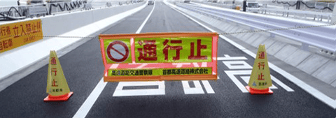 「通行止」という大きな赤字と車両通行止めの標識が付いた、オレンジ色の閉鎖幕。左右に「通行止」と書かれた黄色いコーンが置かれている。