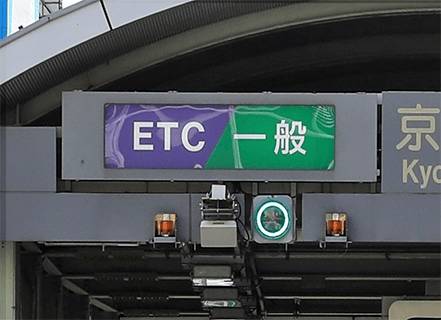 通行可能なレーンの表示例。左半分が紫色の背景で「ETC」、右半分が緑色の背景で「一般」と表示されたサインと、その下で点灯している緑色の信号。
