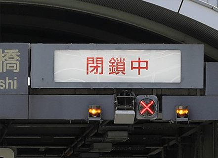 赤字で「閉鎖中」と表示された料金所のレーン表示板。下部には赤色の「×」ランプが点灯している。