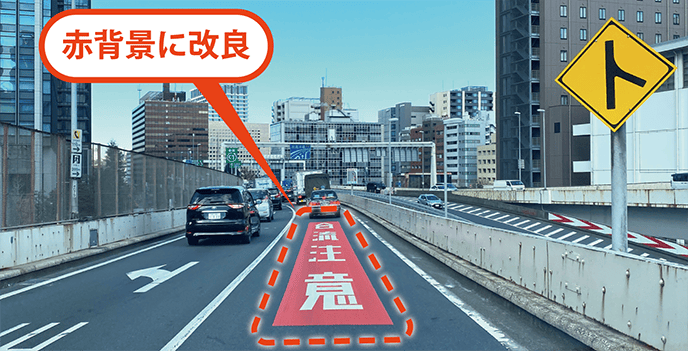 路面文字「合流注意」を、より目立つ赤背景のものへ改良