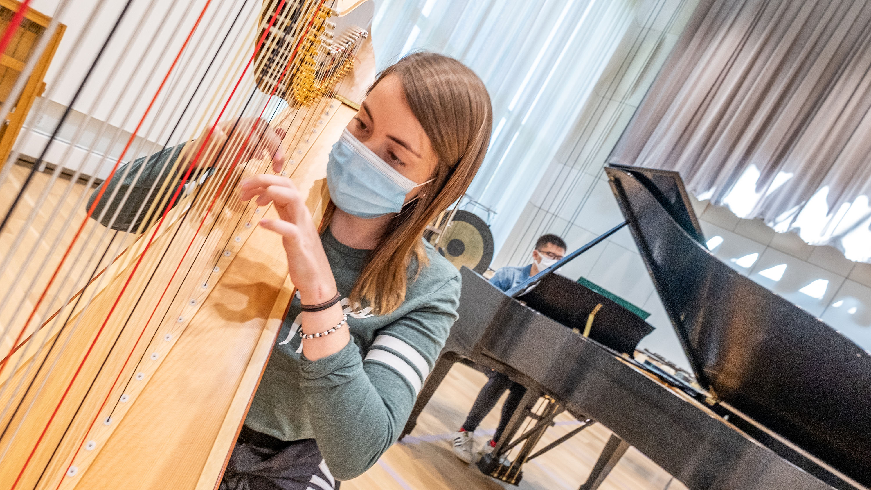 Two masked people playing harp and piano