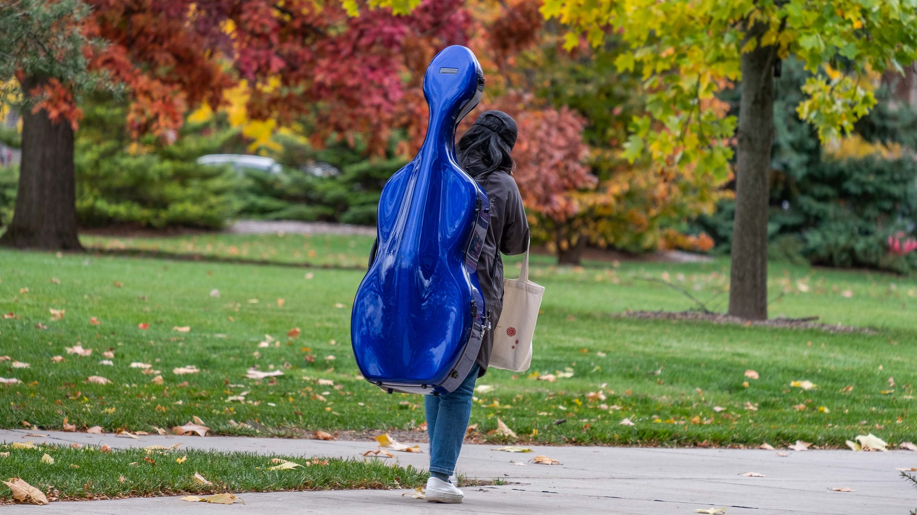 Student walking, with a blue cello case