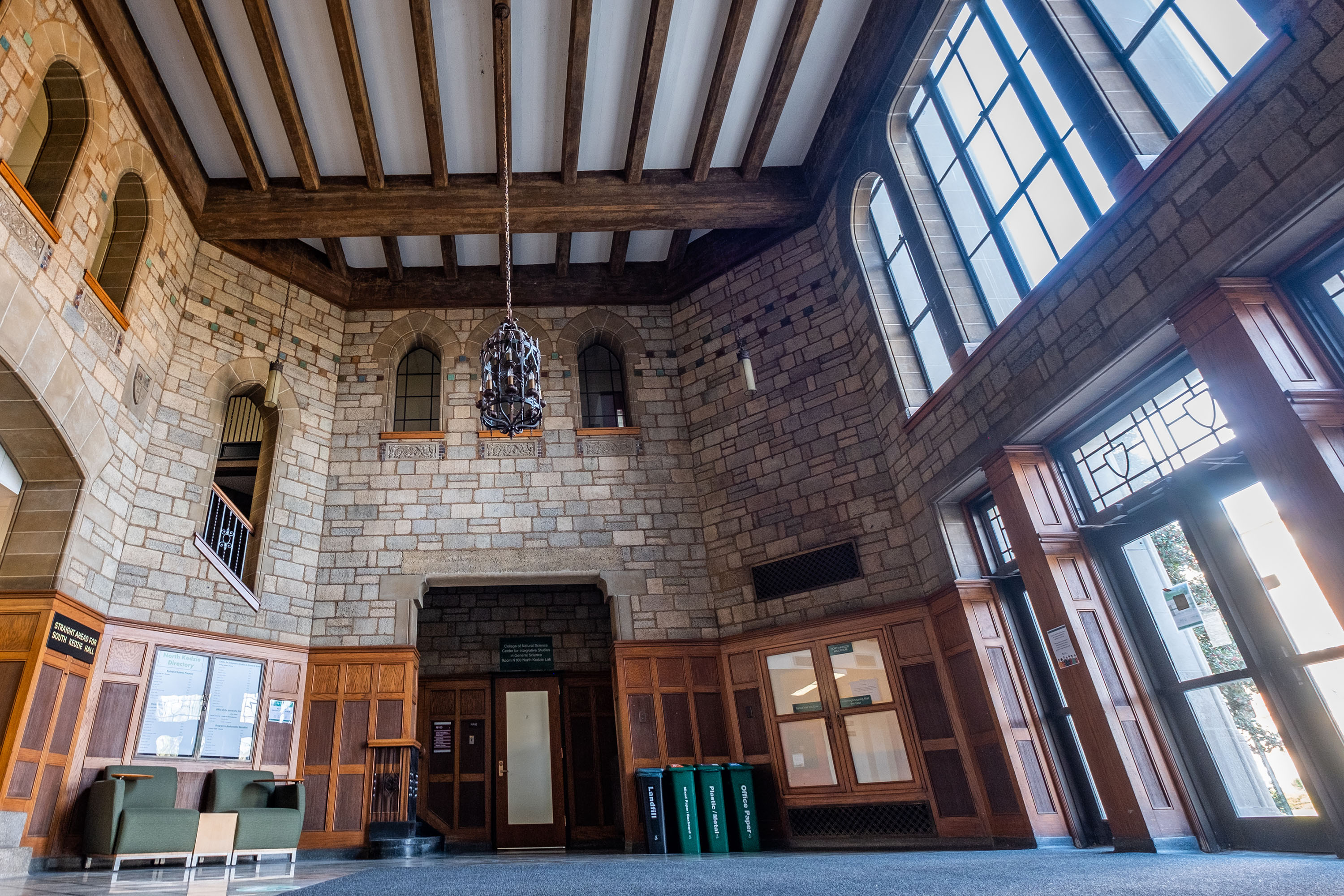 The inside atrium of North Kedzie Hall with stone, wood working and a wrought iron chandelier. 