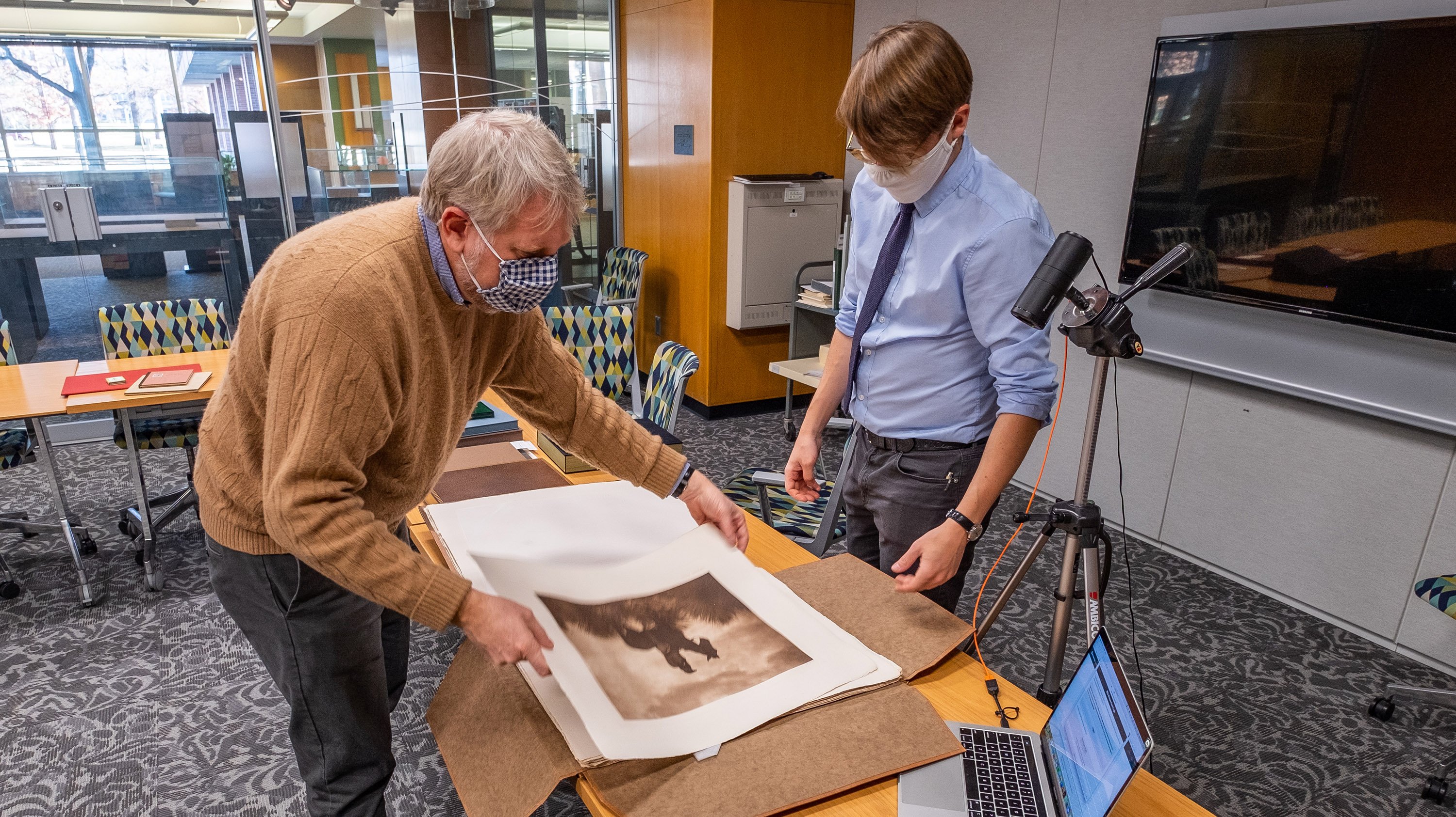Two people examine a photograph from MSU Special Collections