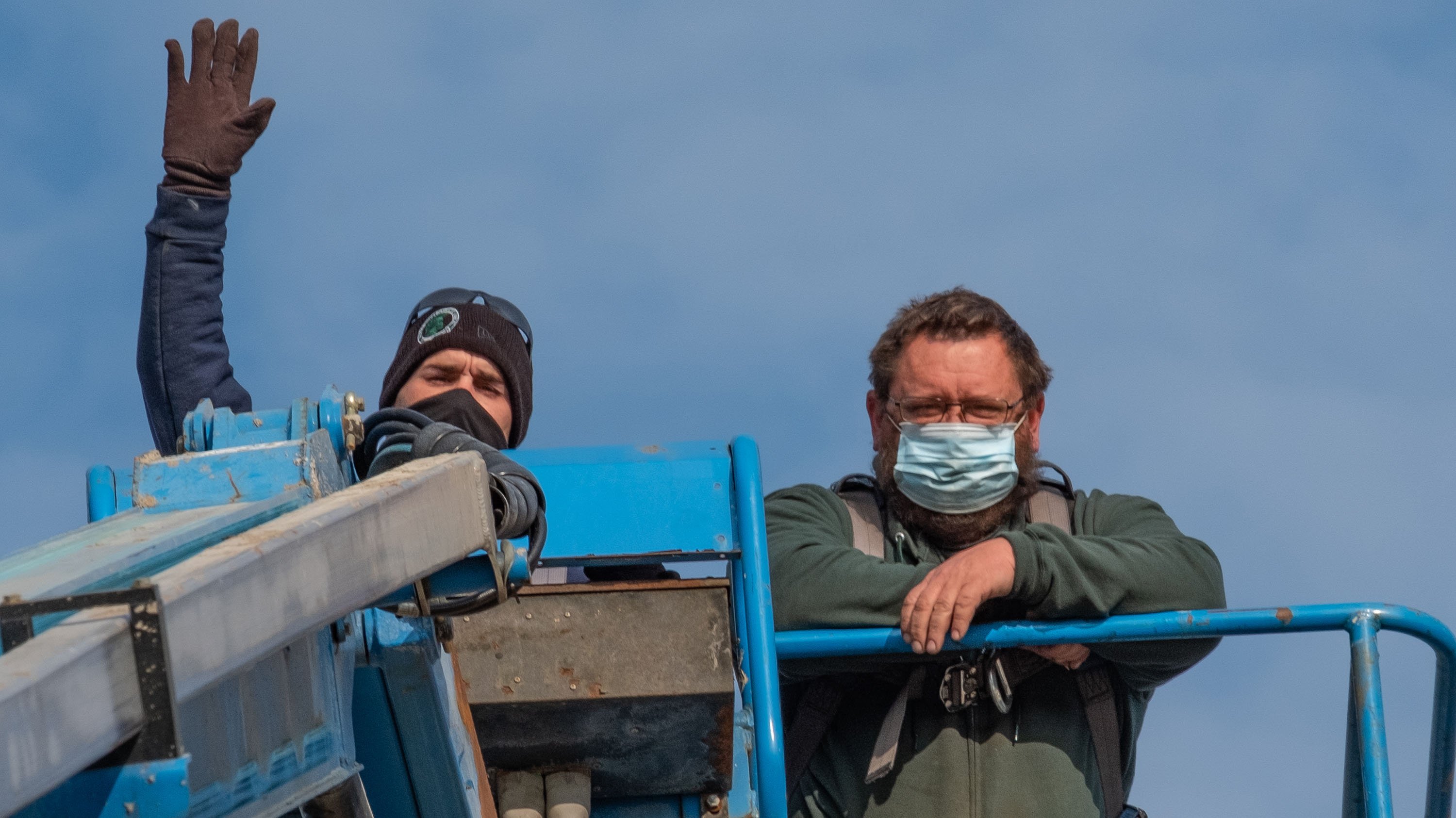 An IPF employee waving from a cherry-picker