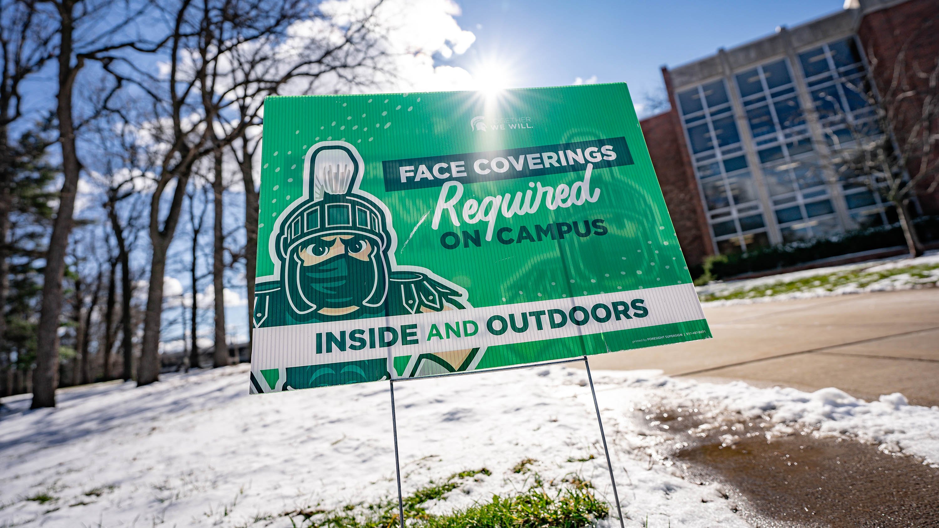 A sign on campus reminding visitors face coverings are required