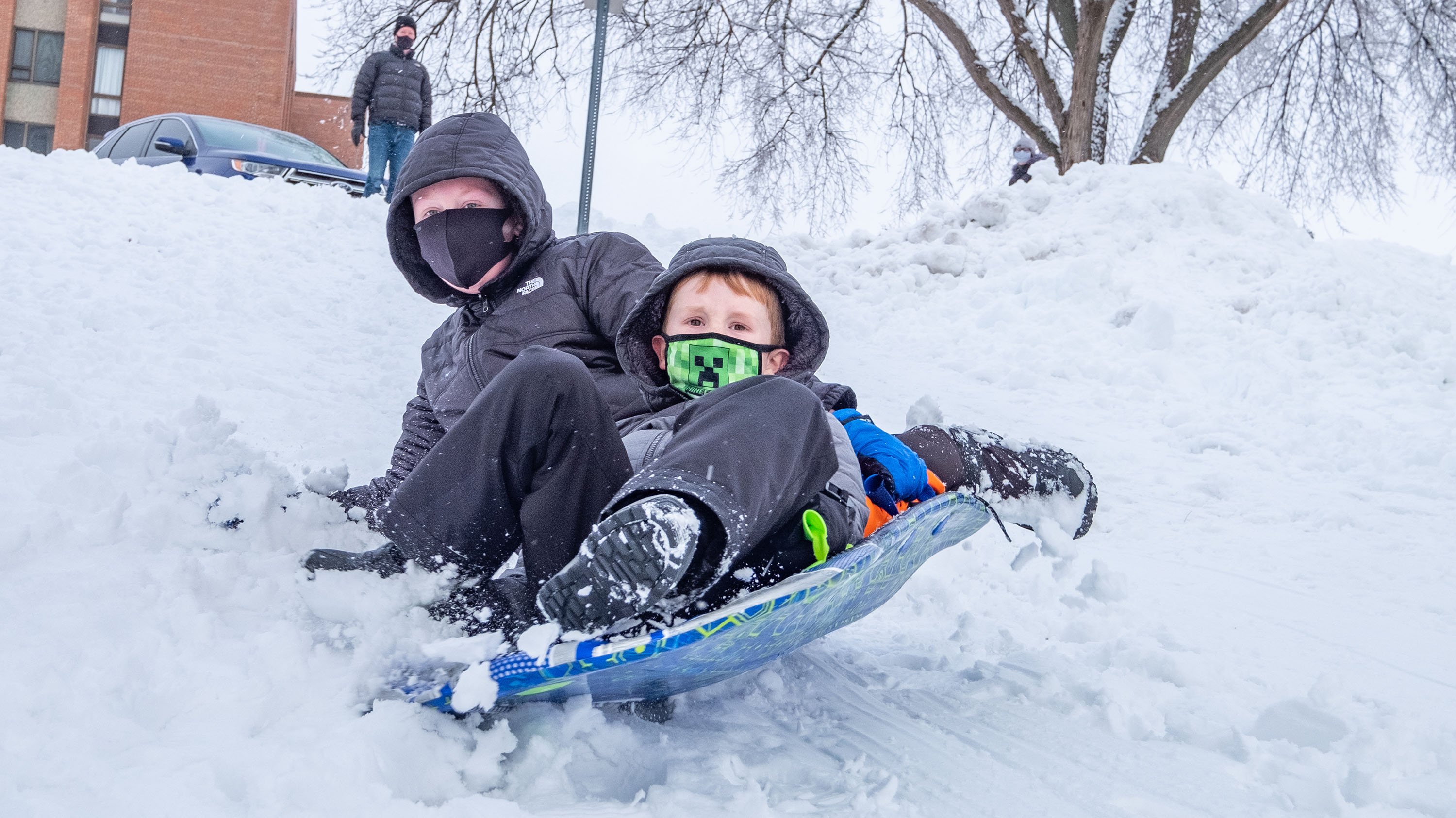 Two boys sledding down a hill