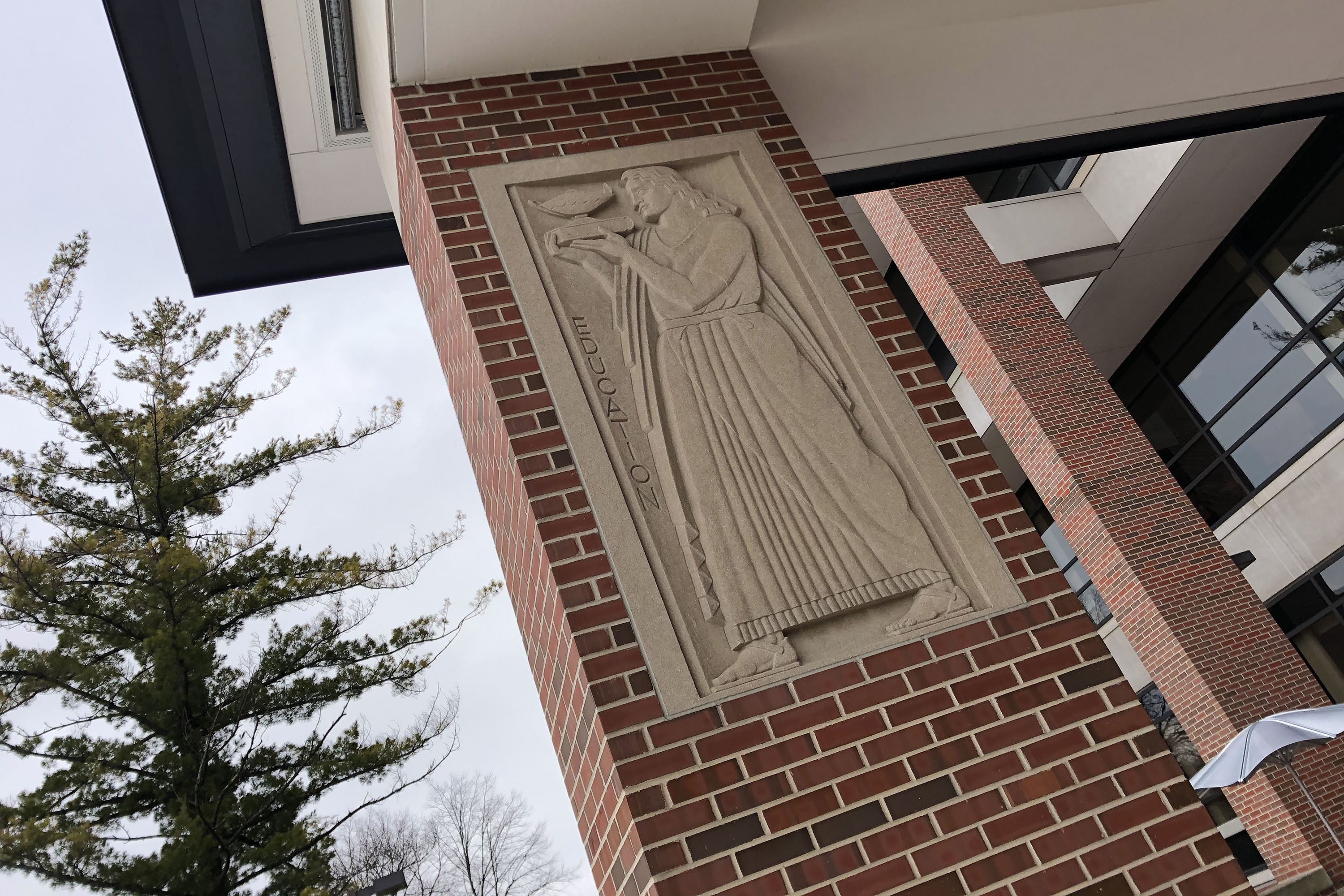 Bas relief etching of a scholar with the word 'education' on a pillar at the Law College. 