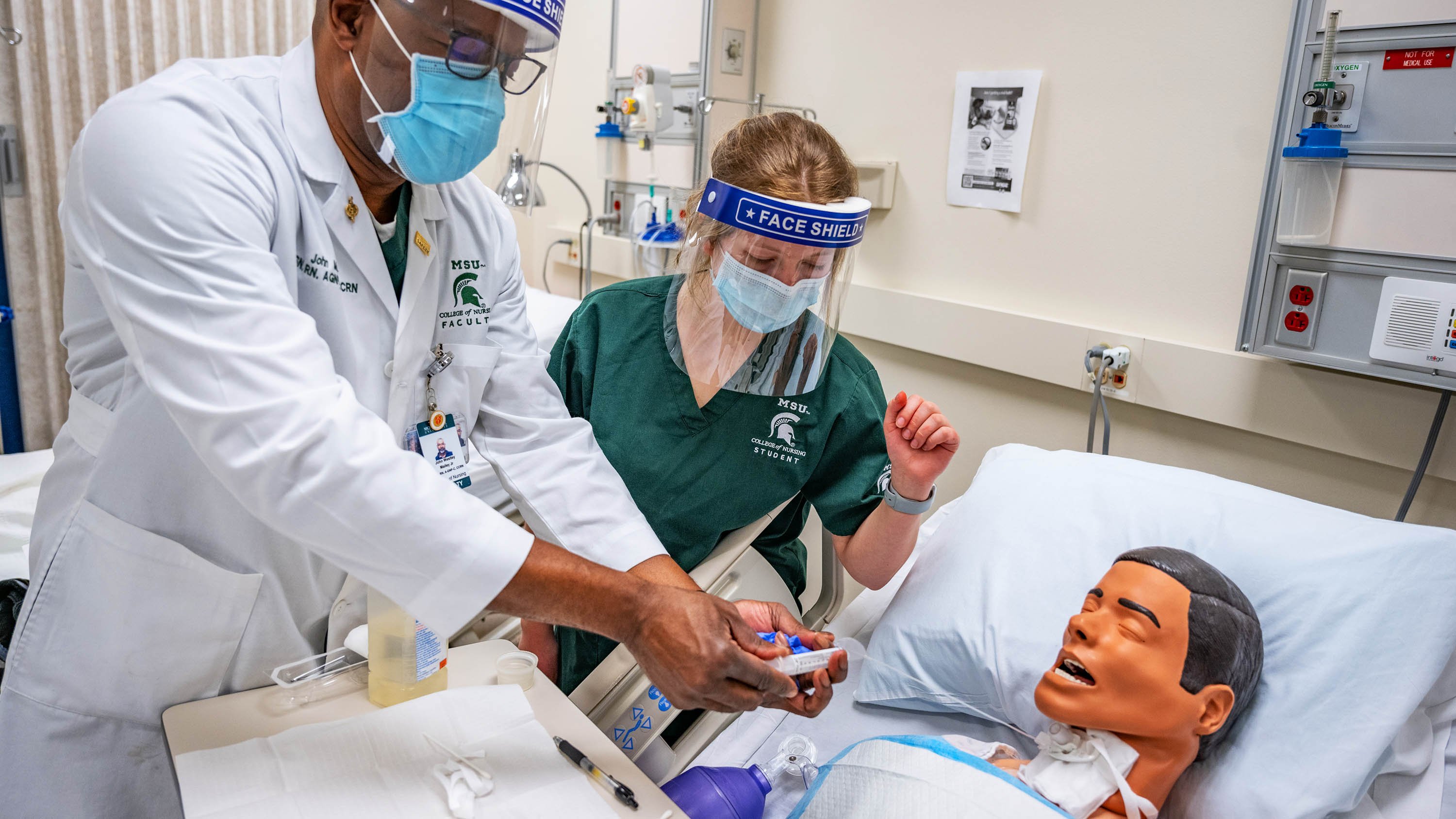 Instructor and student working with dummy in nursing class