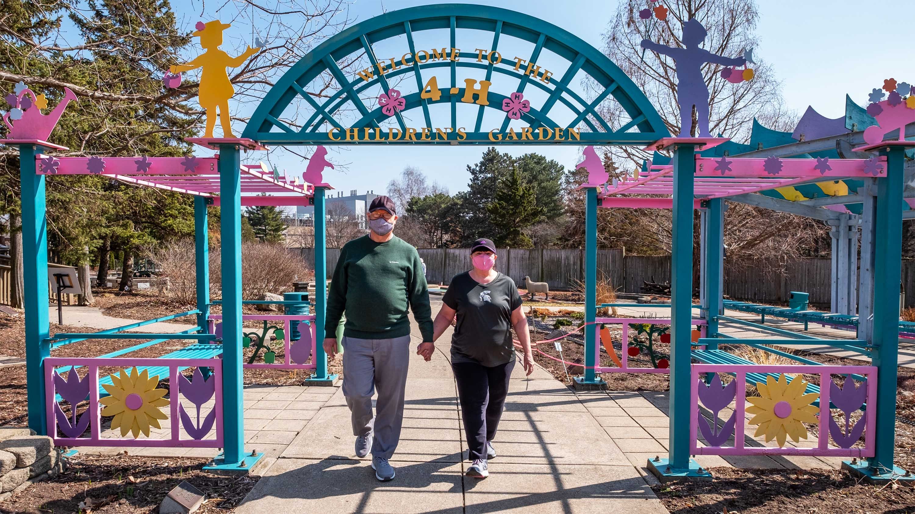Two people in masks walking through the 4-H children's garden
