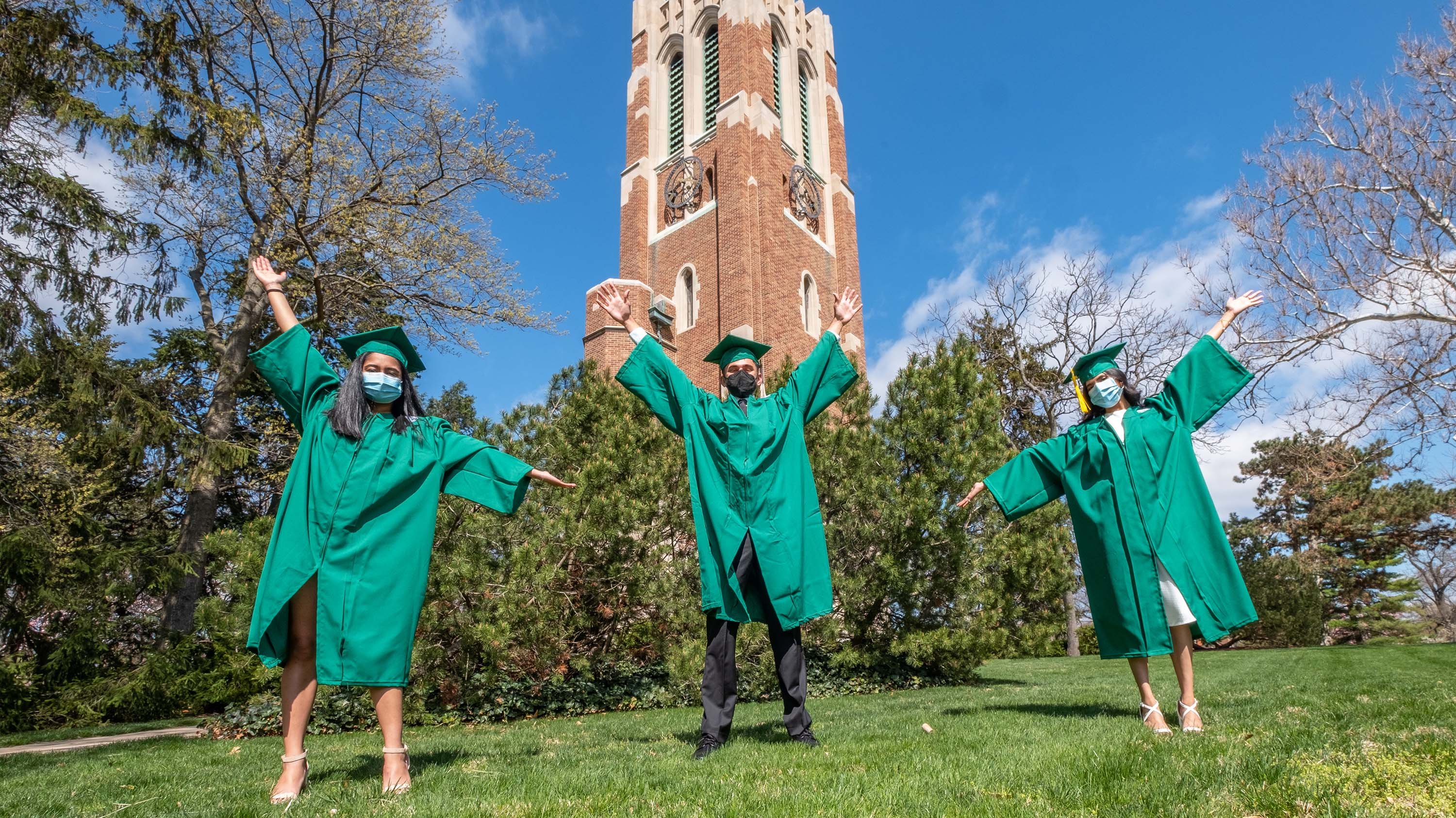 Three MSU grads in front of Beaumont Tower
