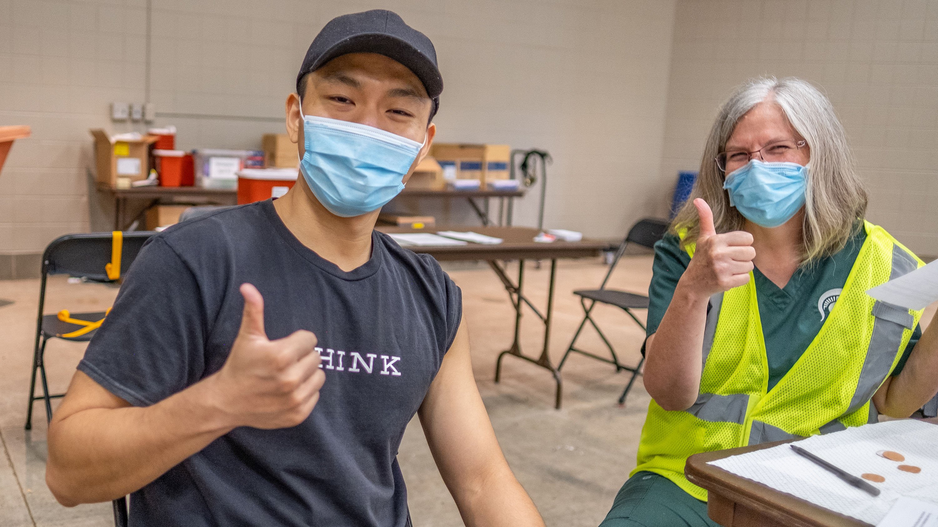 Student and health care worker giving thumbs-up gesture in the MSU vaccination clinic