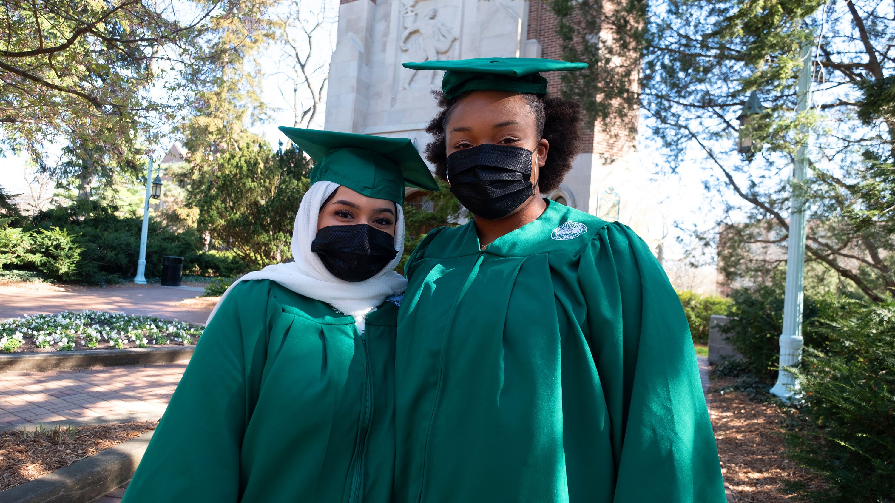 Two MSU grads in front of Beaumont Tower 