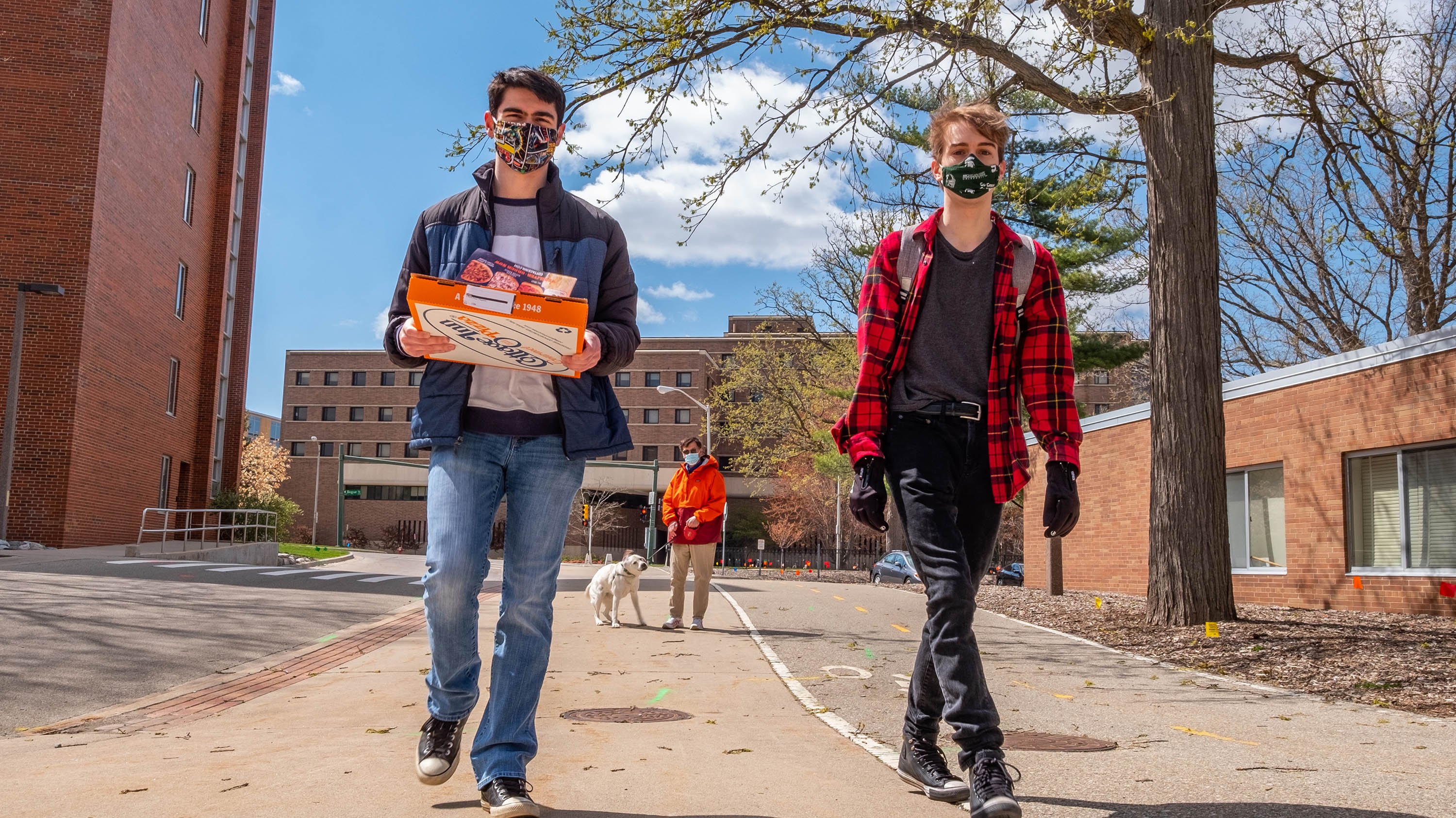 Students walking with pizza box