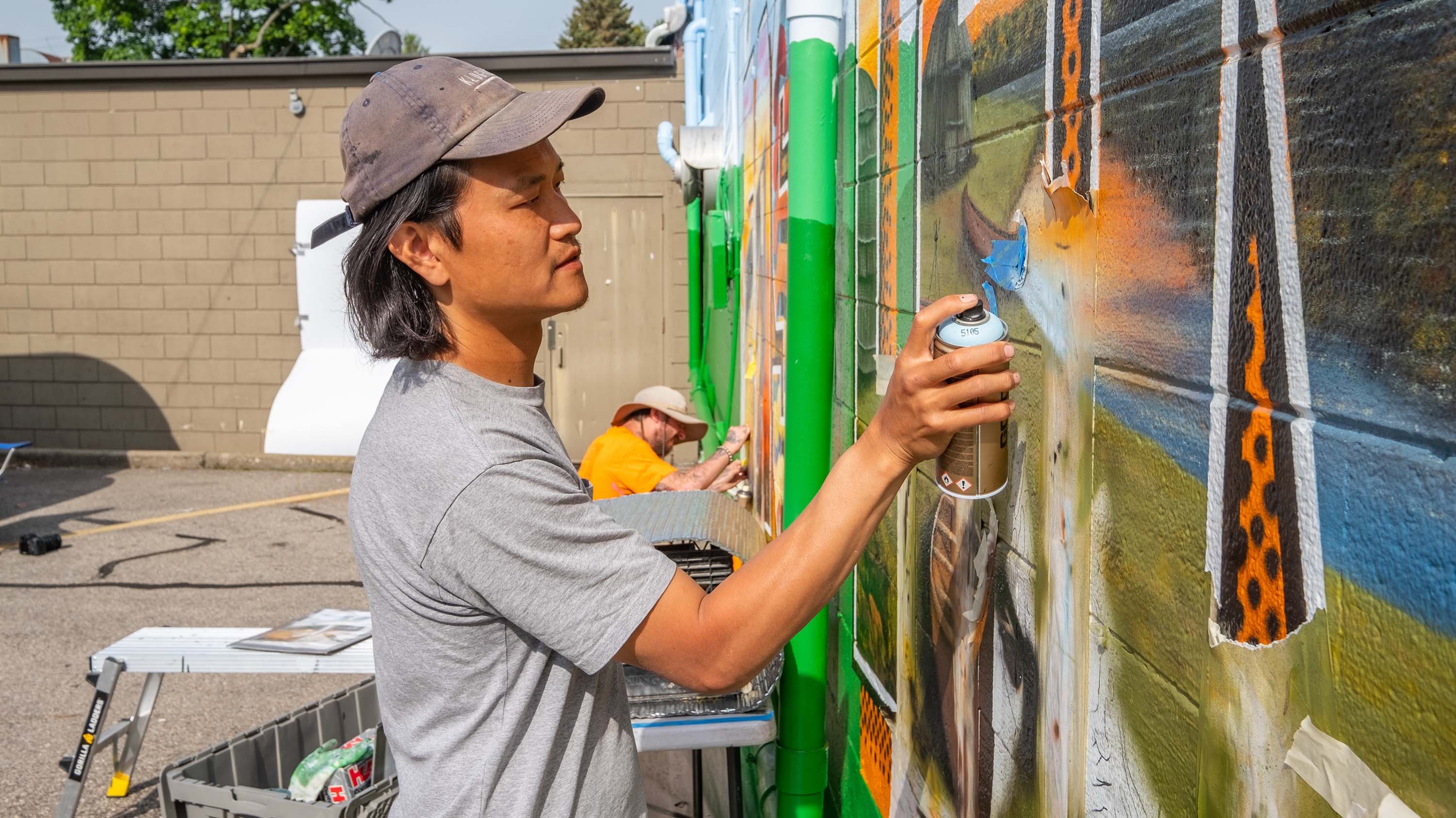 Two people painting a mural with spray paint
