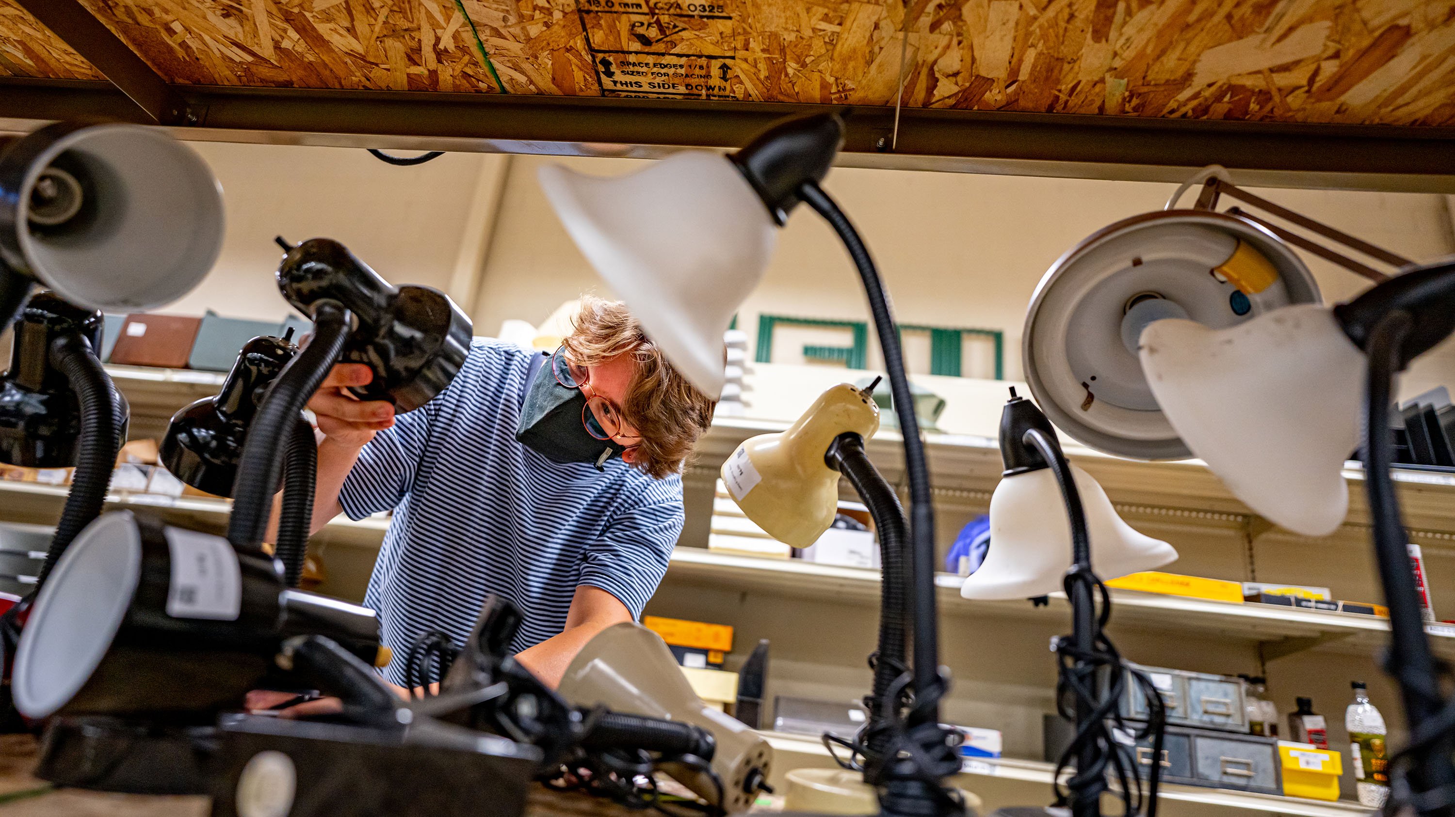 Person looking at desk lamps on a shelf in the MSU surplus store