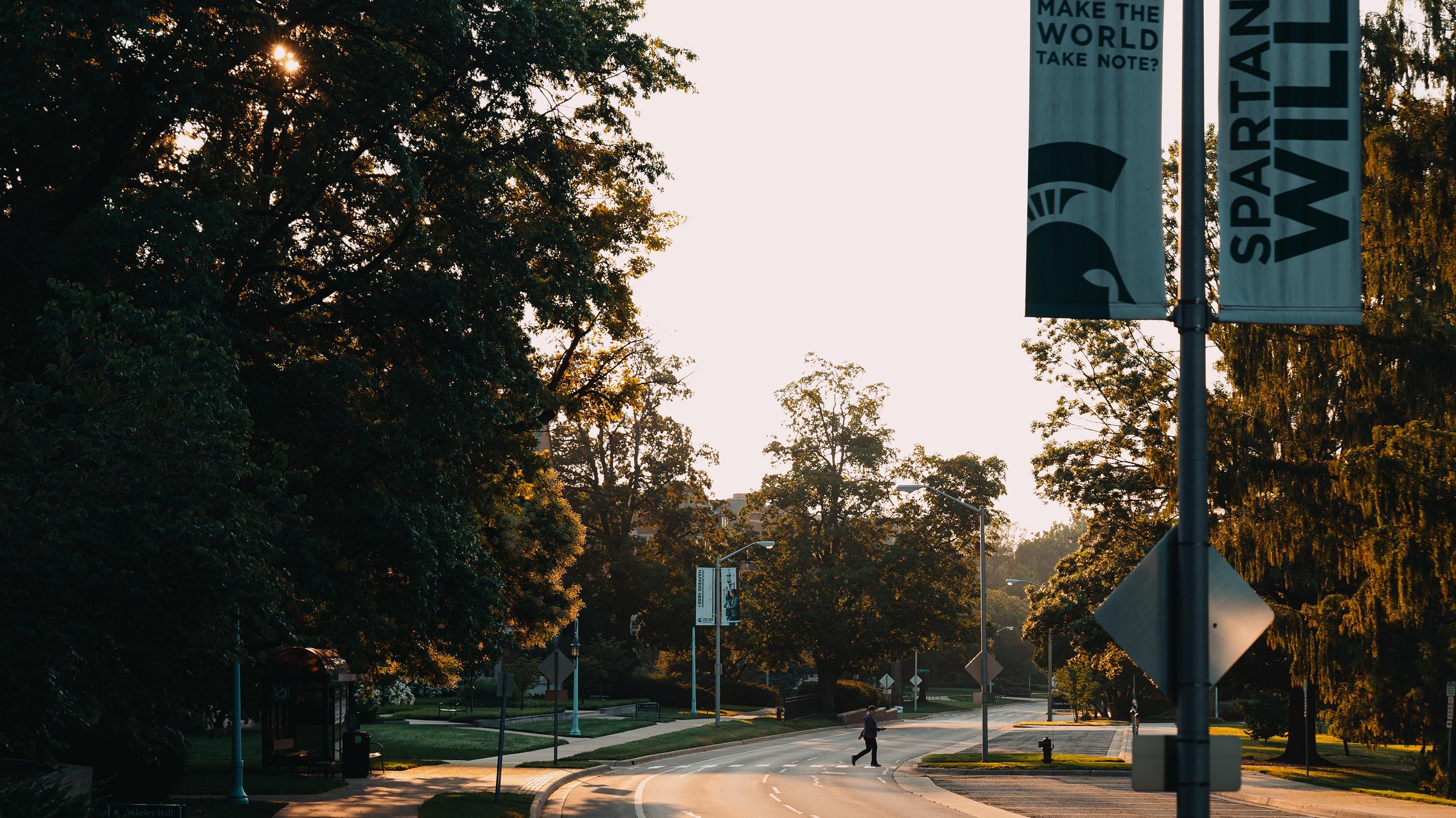 Person walking across the street during sunset on West Circle Drive
