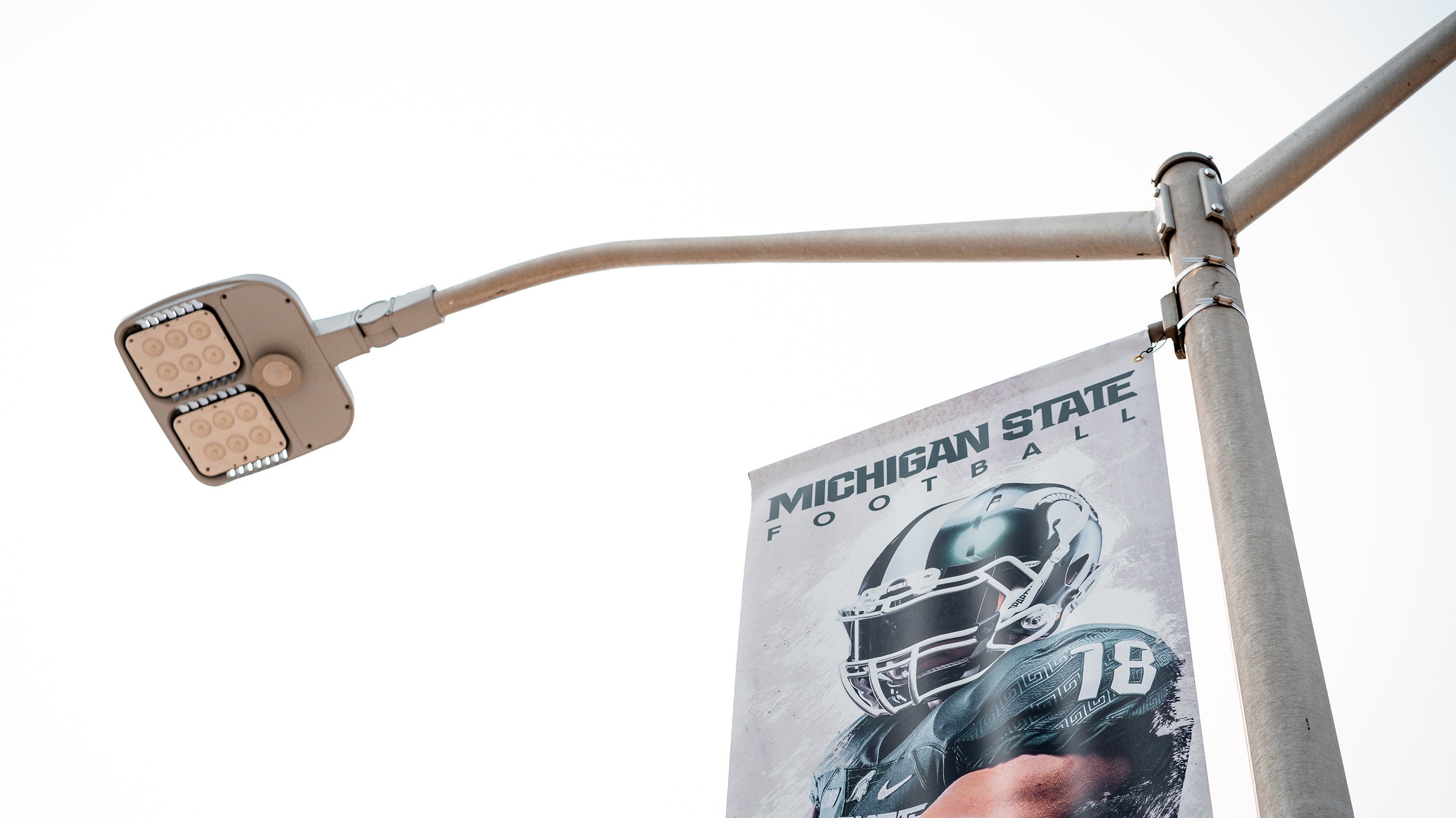 Banner advertising MSU football season on a streetlight in front of Spartan Stadium