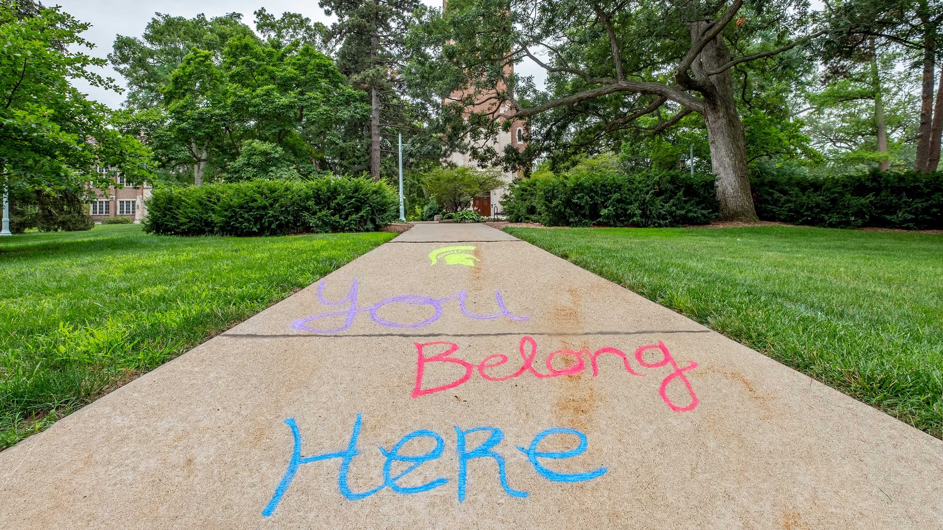 Sidewalk in front of Beaumont Tower with words written in chalk: 'You belong here'