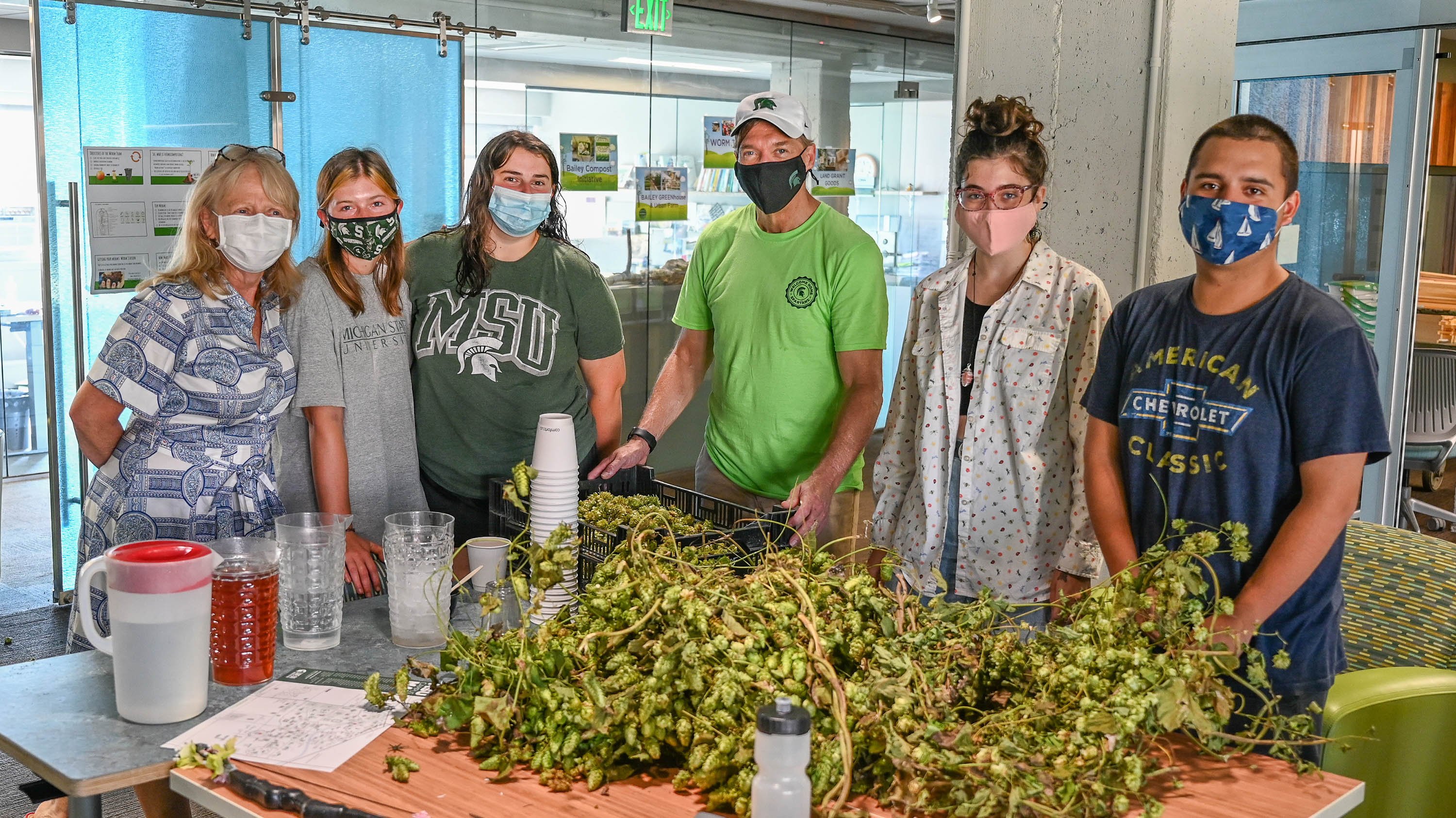 Members of RISE and President Stanley standing behind a table with a bushel of hops on it