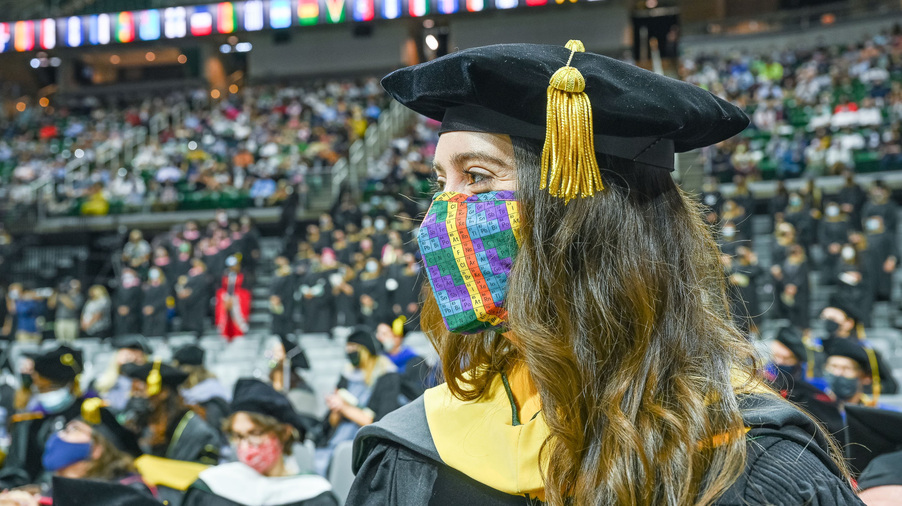 Grad with periodic table-printed mask at Graduate Degree commencement ceremony