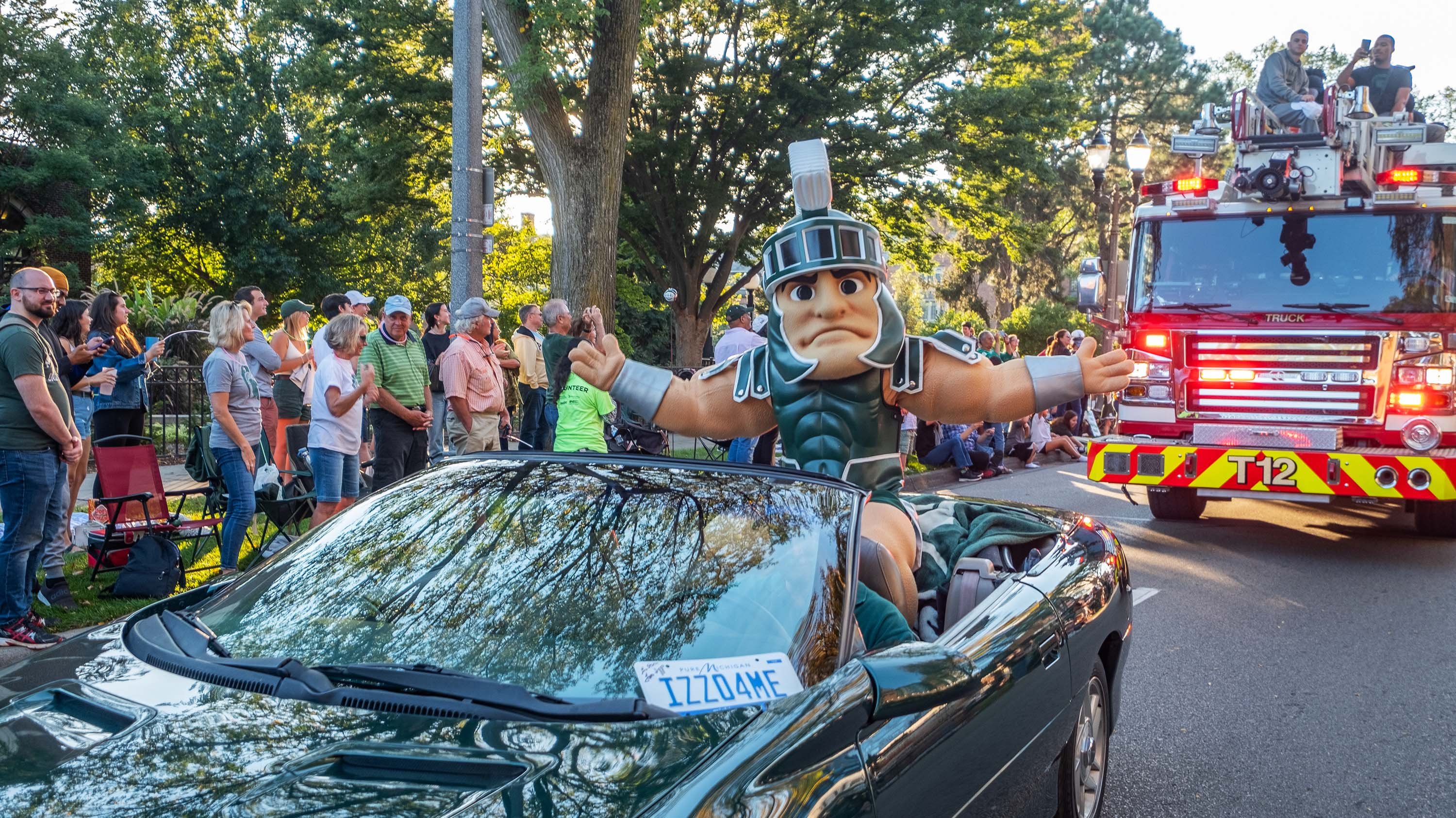 Sparty riding in convertible at homecoming parade