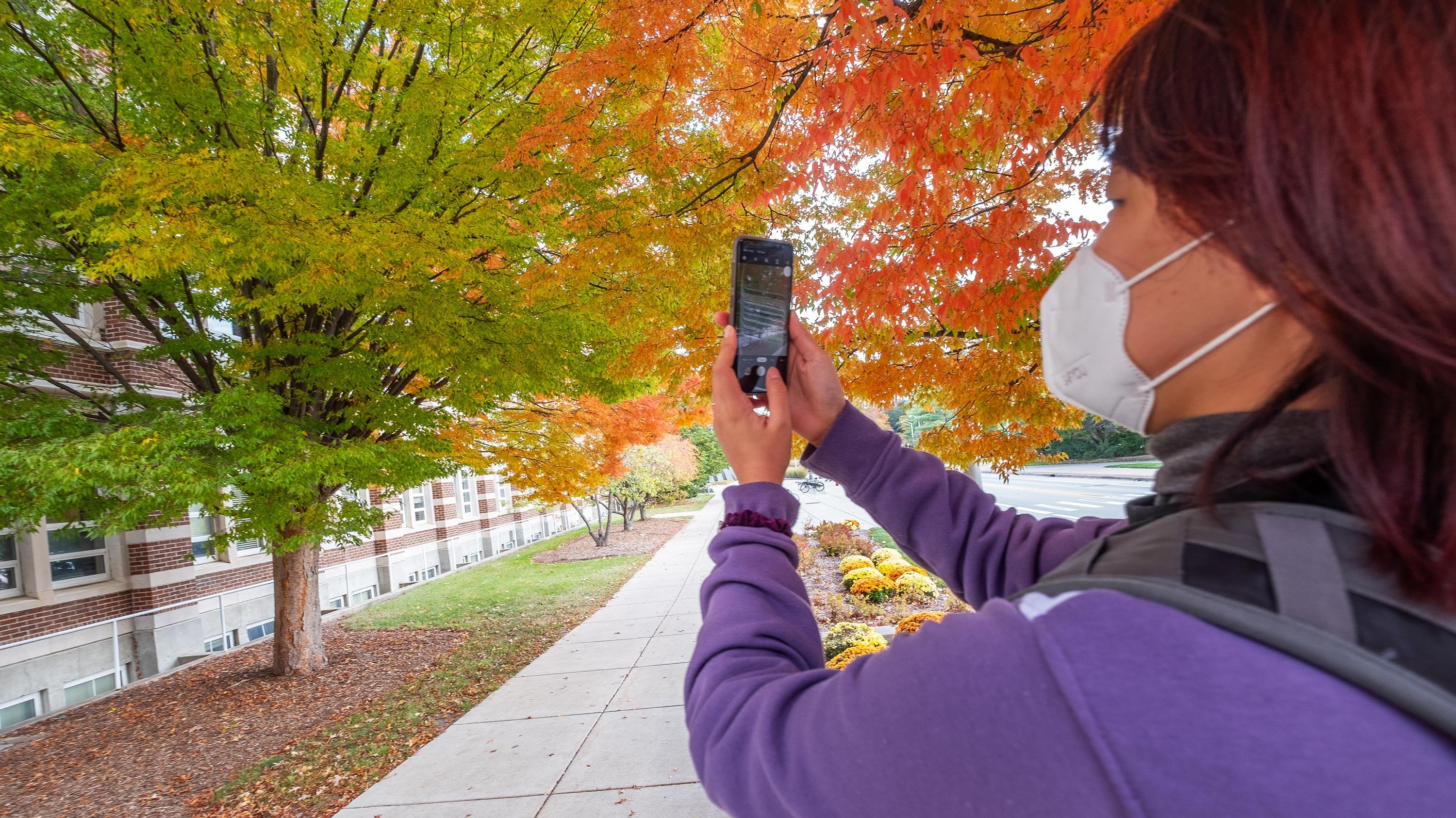 Student taking a picture of fall colors on campus