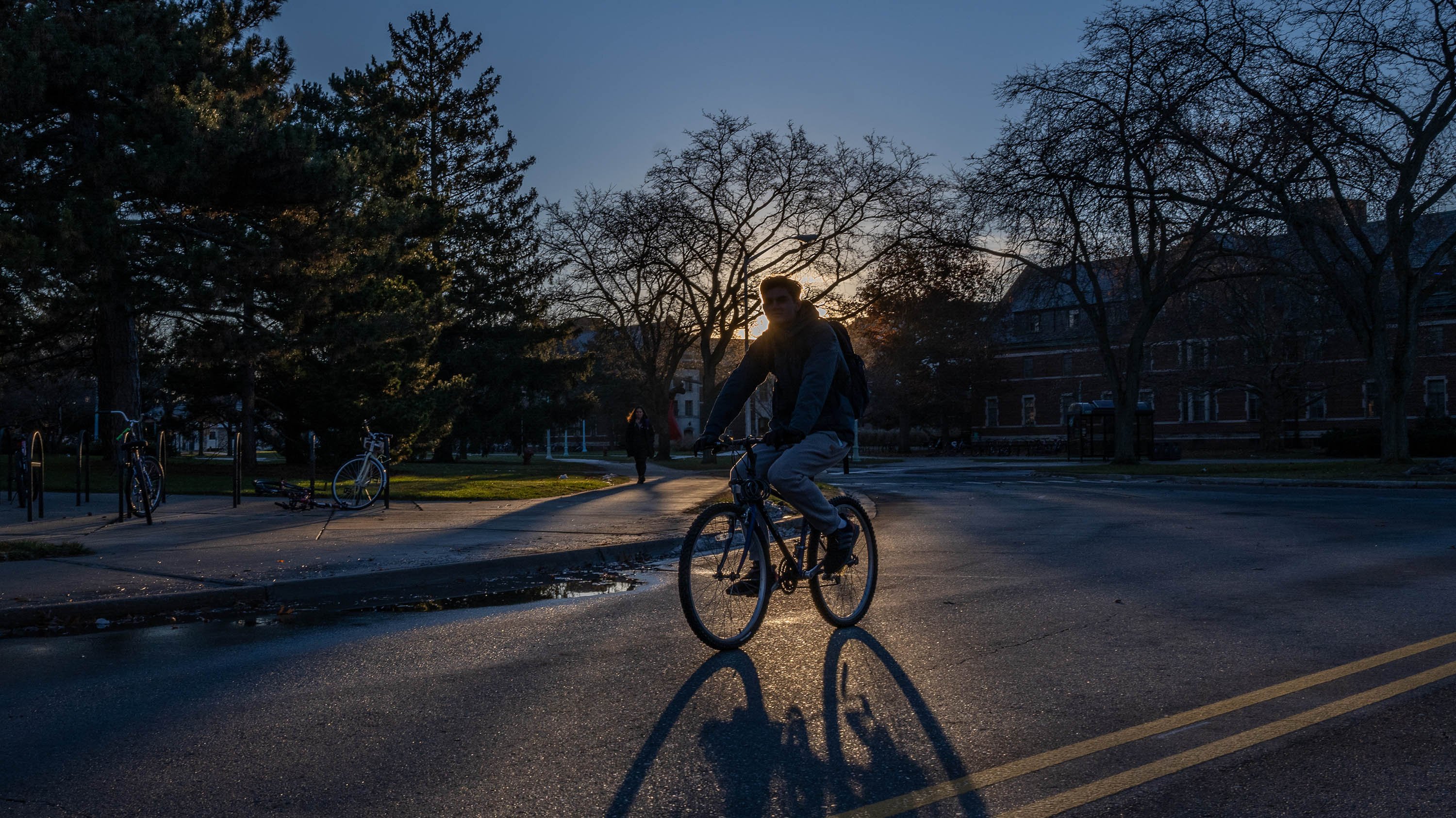 Silhouette of a figure riding their bike, illuminated by the rising sun