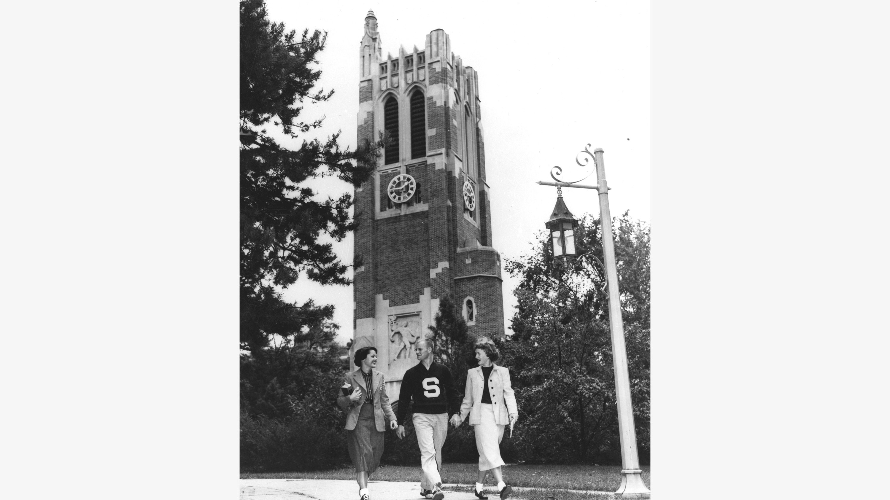 Black and white photograph of three people walking near Beaumont Tower