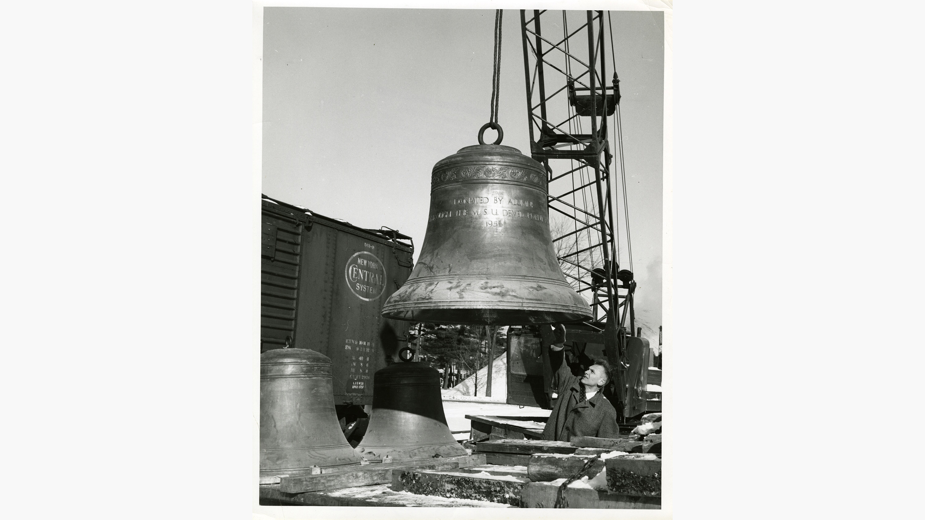 Black and white photo of a bell being installed