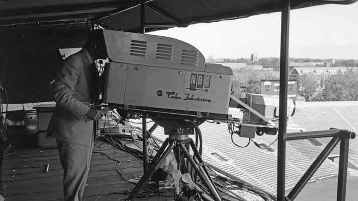 Black and white image of a camera operator and a large camera in Spartan Stadium