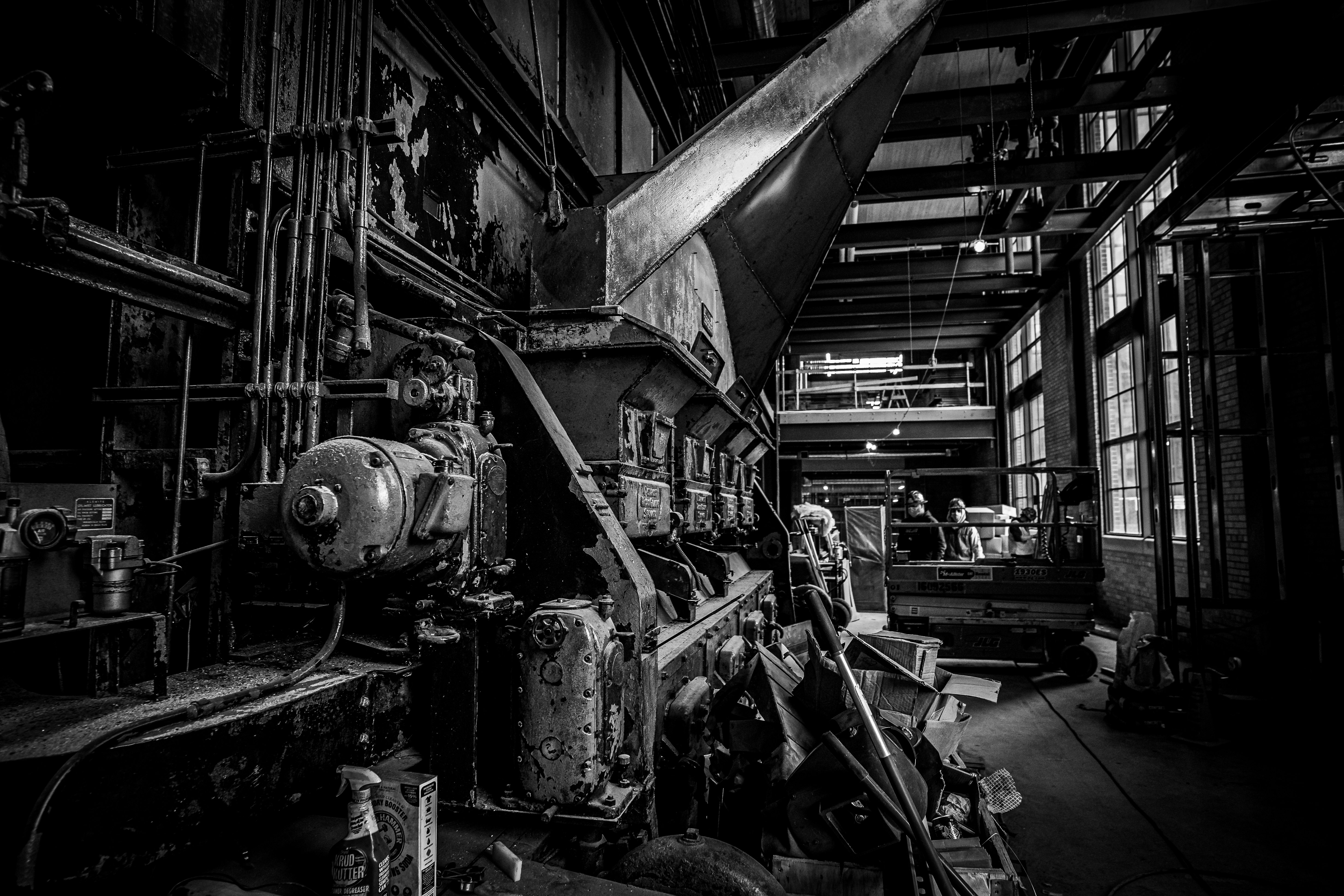 A black-and-white photograph shows workers near the metal boiler of the old Shaw Lane Power Plant that has been integrated into the new STEM Teaching and Learning Facility. 