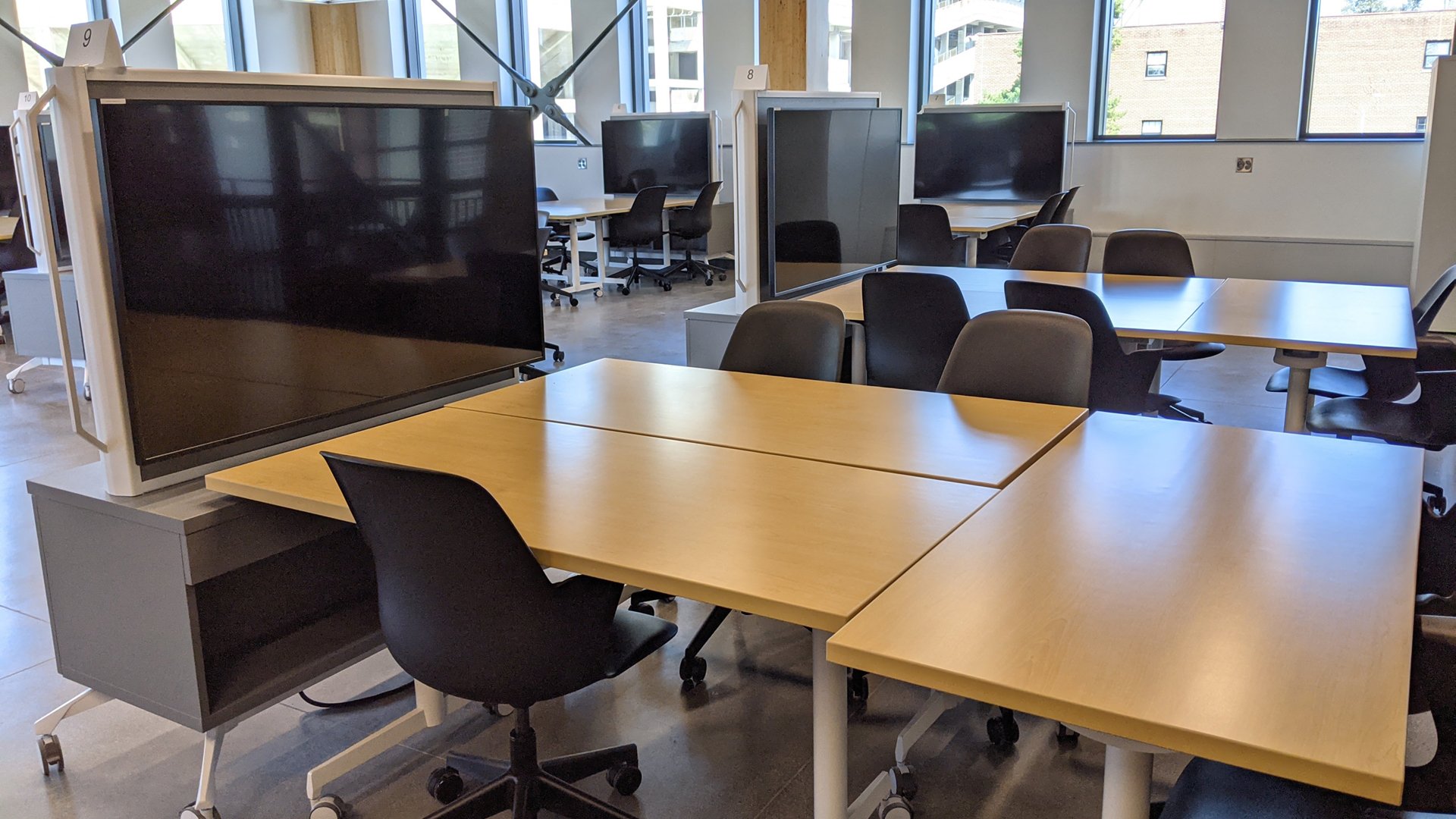 A photograph from inside a computer science classroom shows several large-screen displays that are mounted to carts so they can be easily moved to different workstations.