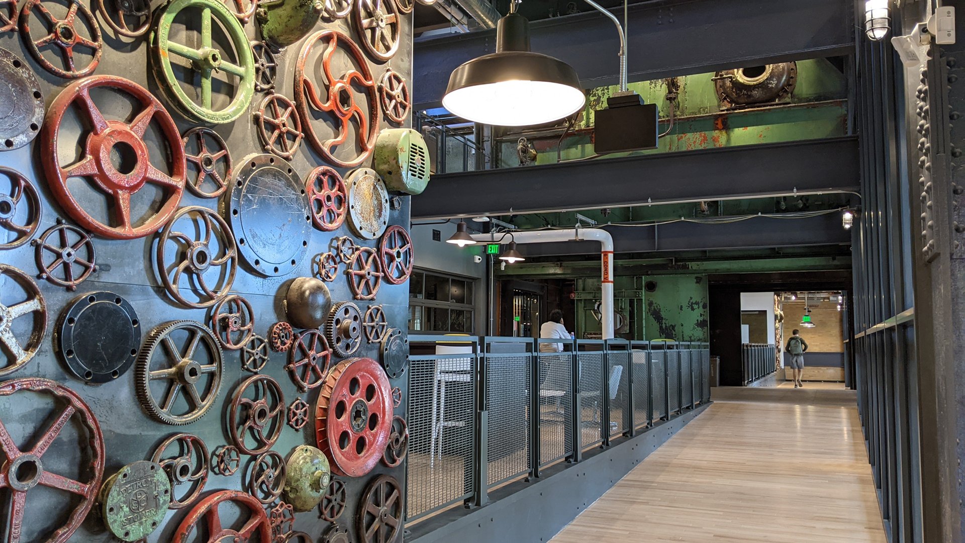 A photograph from inside the new STEM Teaching and Learning Facility shows an art wall made from handwheels, valves and gears recovered from MSU's Shaw Lane Power Plant.