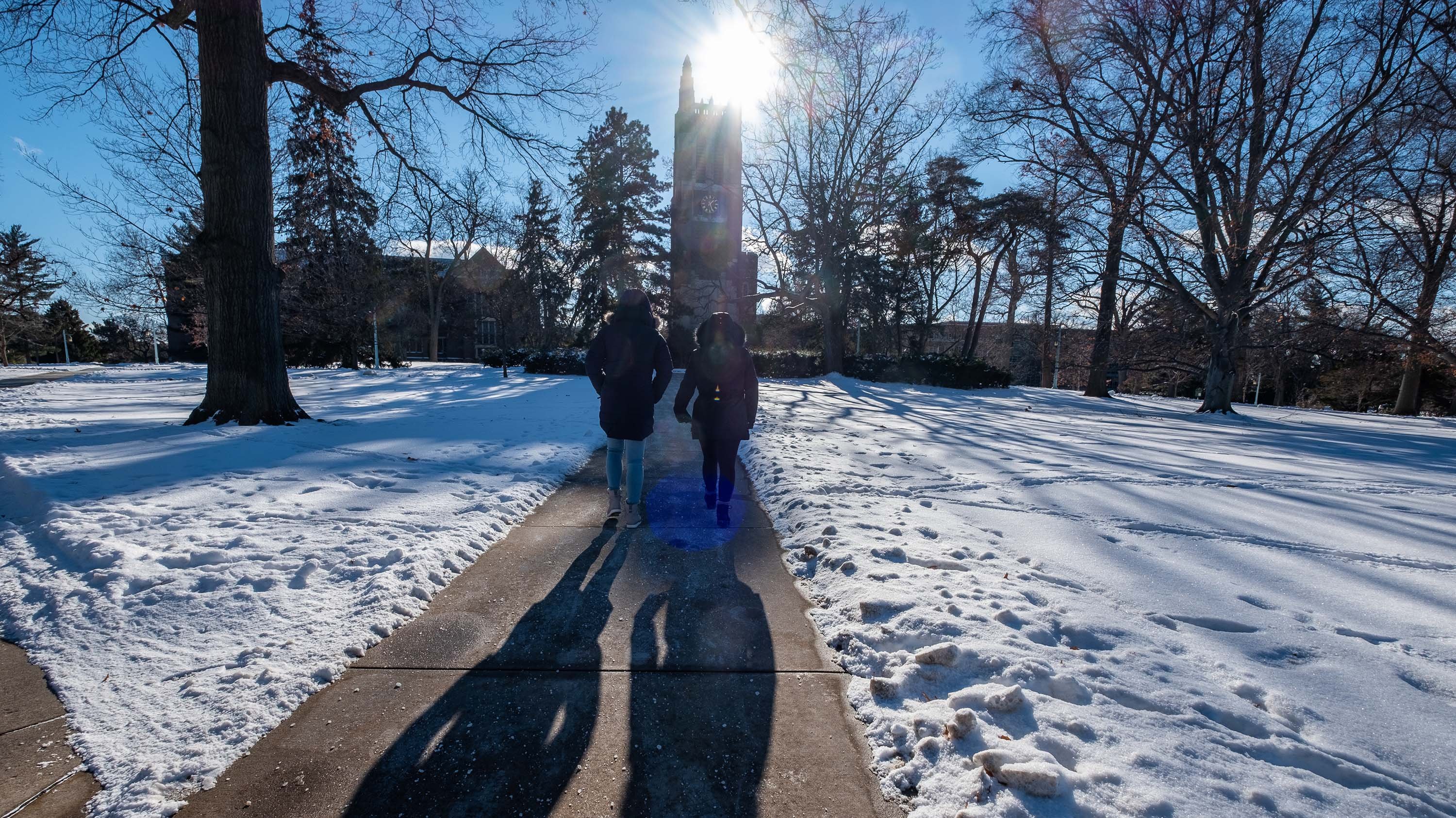 Two people walk in front of Beaumont tower