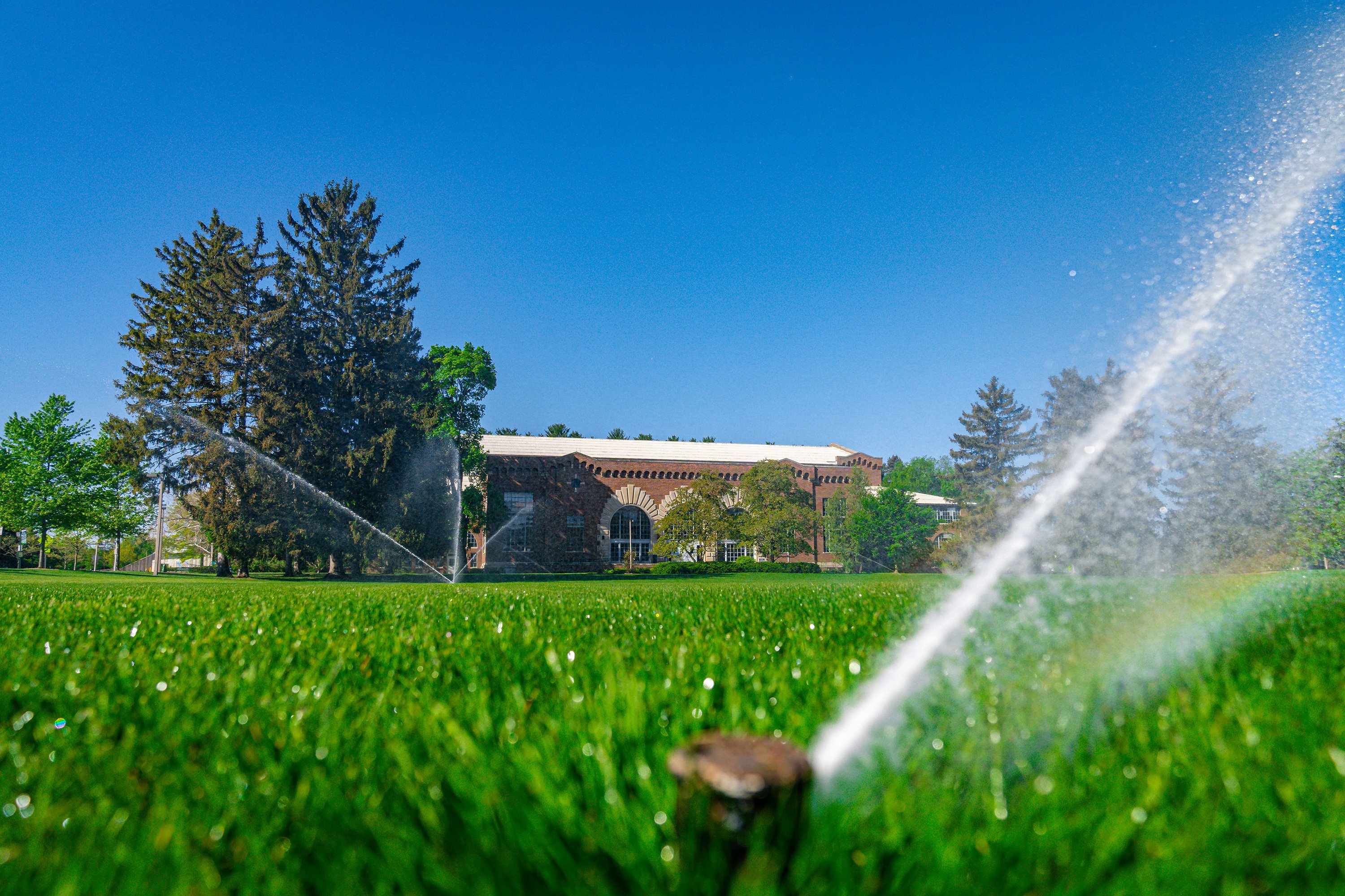 sprinkler spraying water with Demonstration Hall in the distance