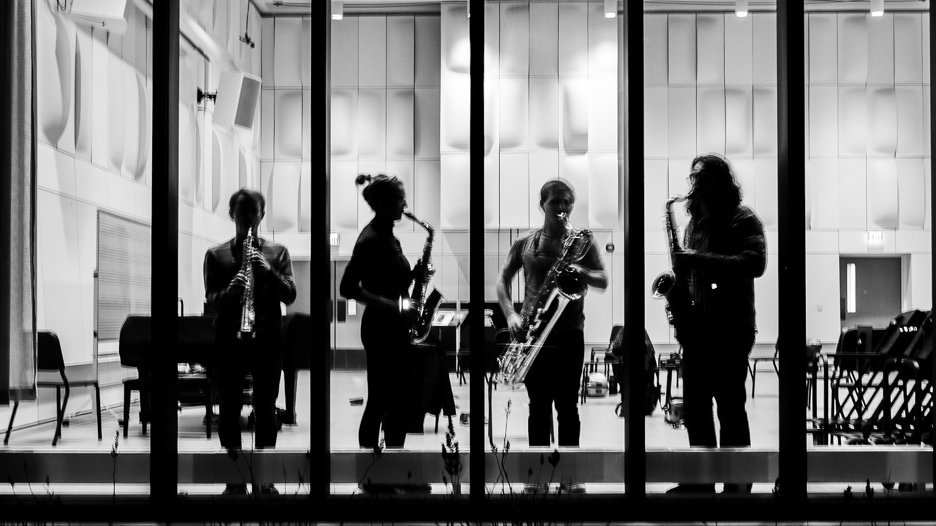 Four College of Music students seen playing instruments through window