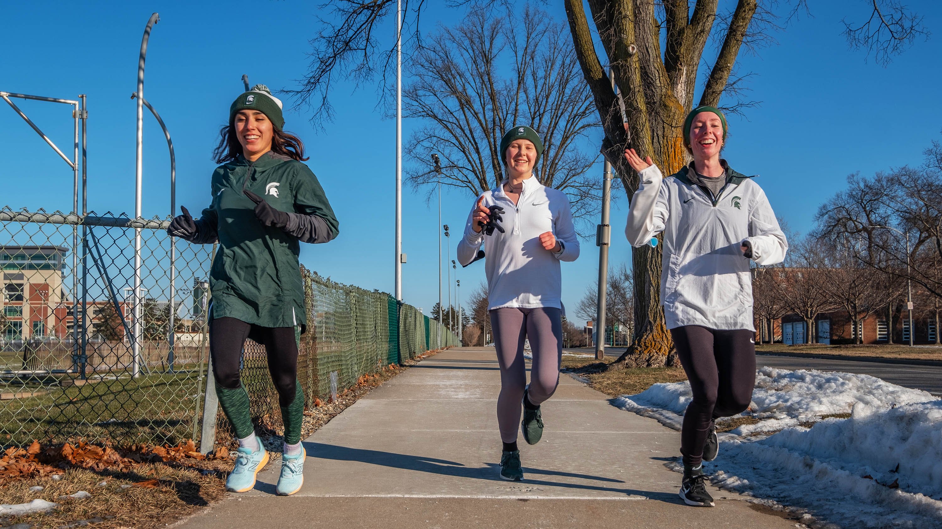 Three students running on campus