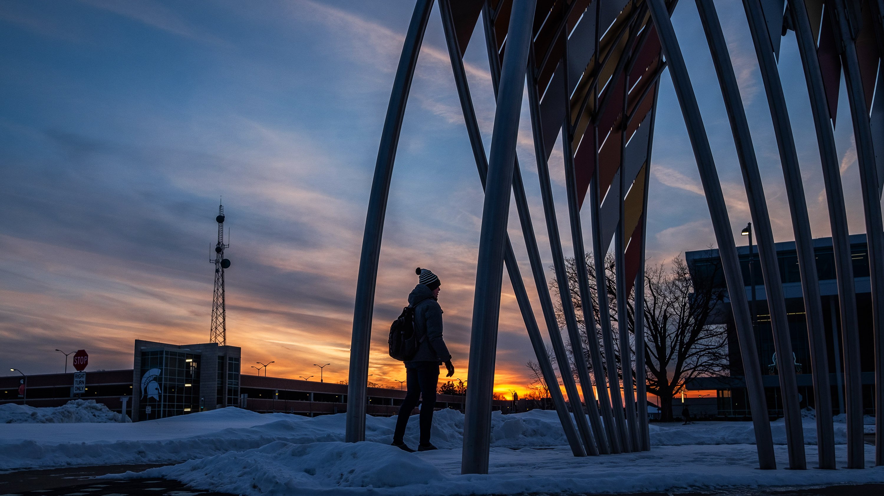 Person walking near 'Victoria' sculpture at sunset