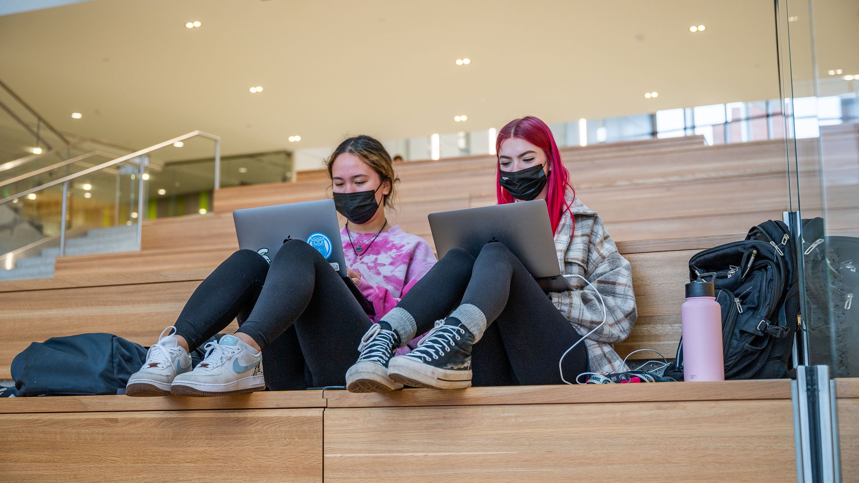 Two students with laptops studying on the Grand Staircase of the Minskoff Pavilion