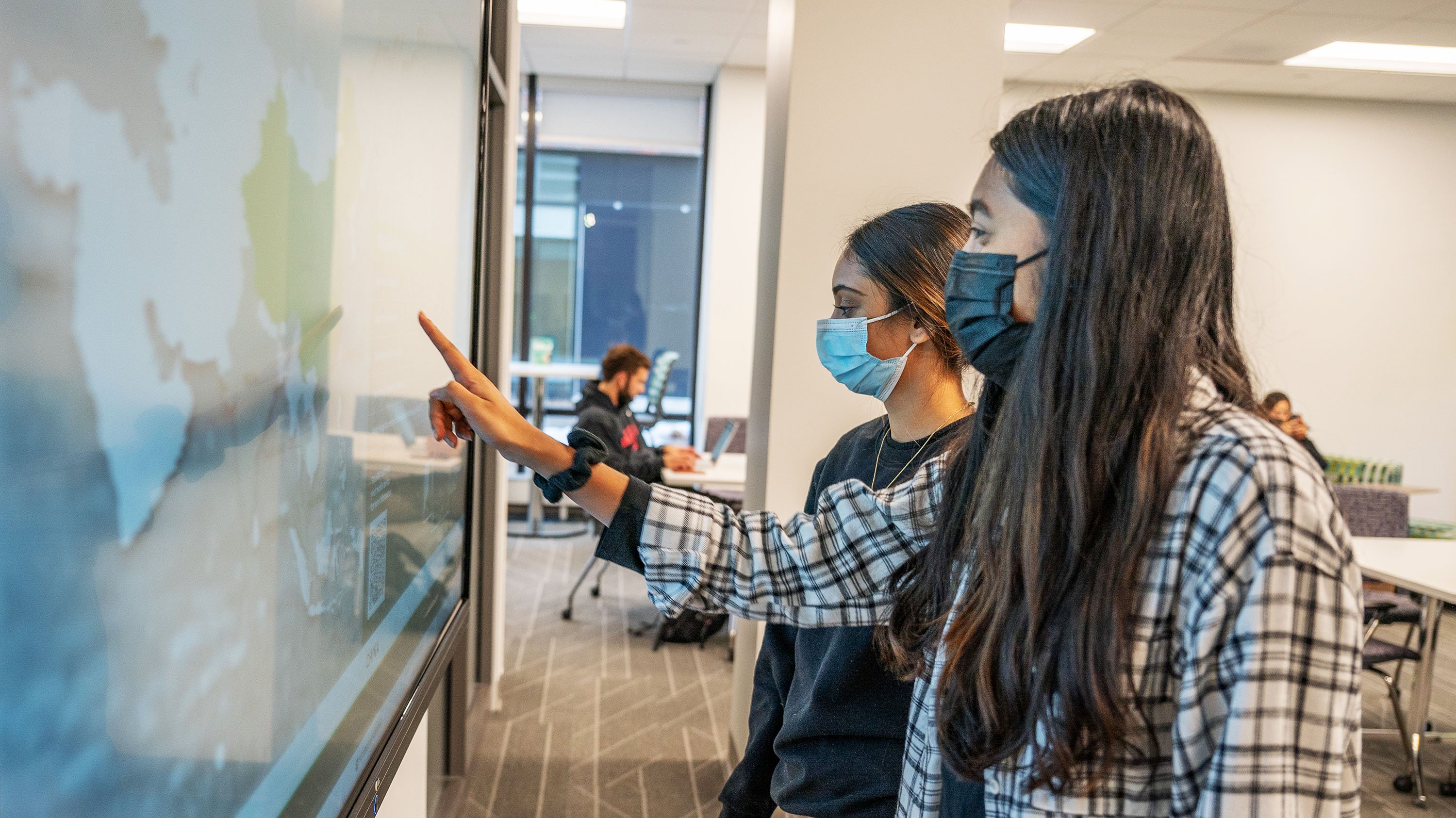 Two students using a touchscreen in the Minskoff Pavilion's study rooms