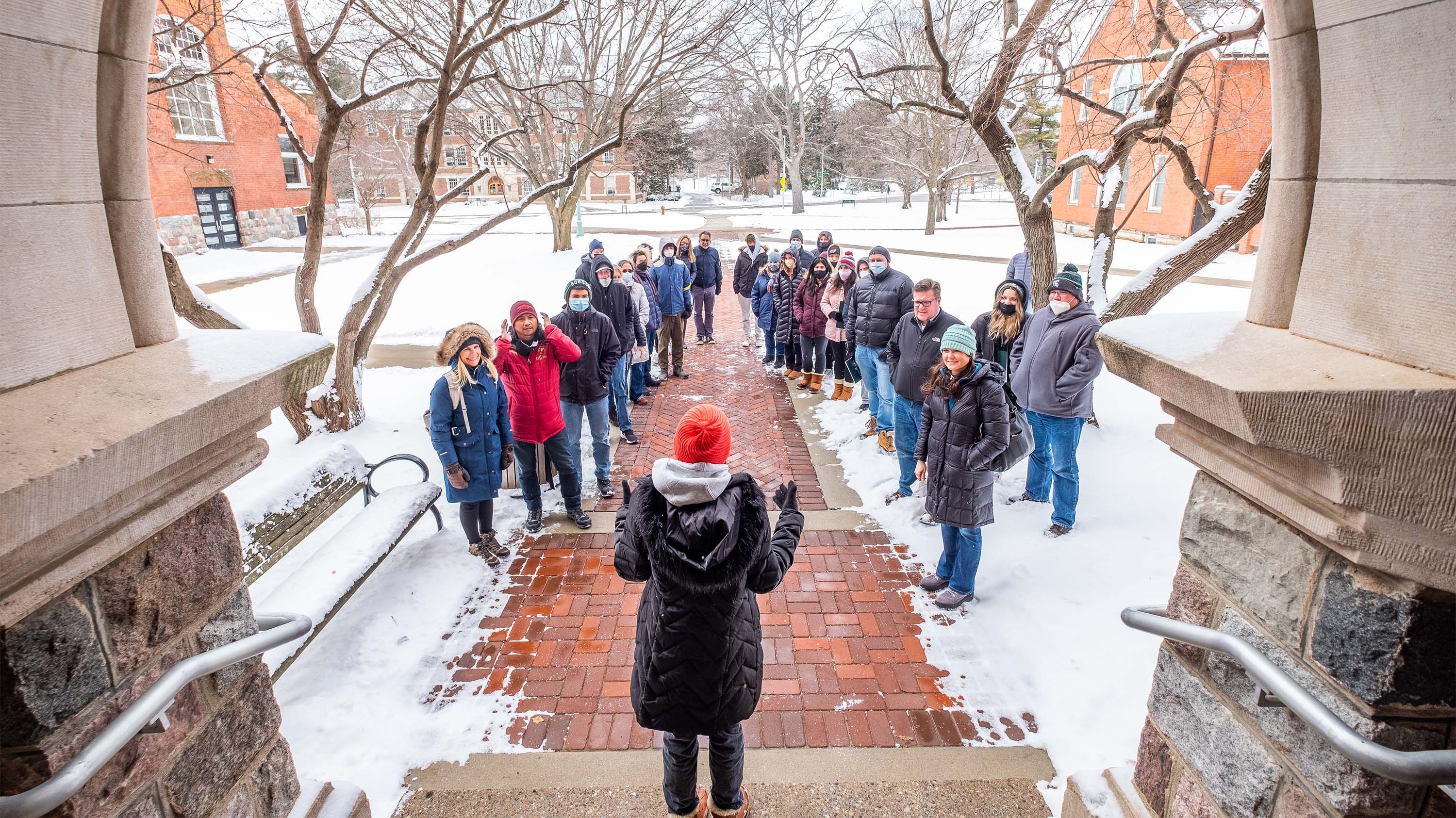 Student tour guide with guests in front of Marshall-Adams Hall on a winter day