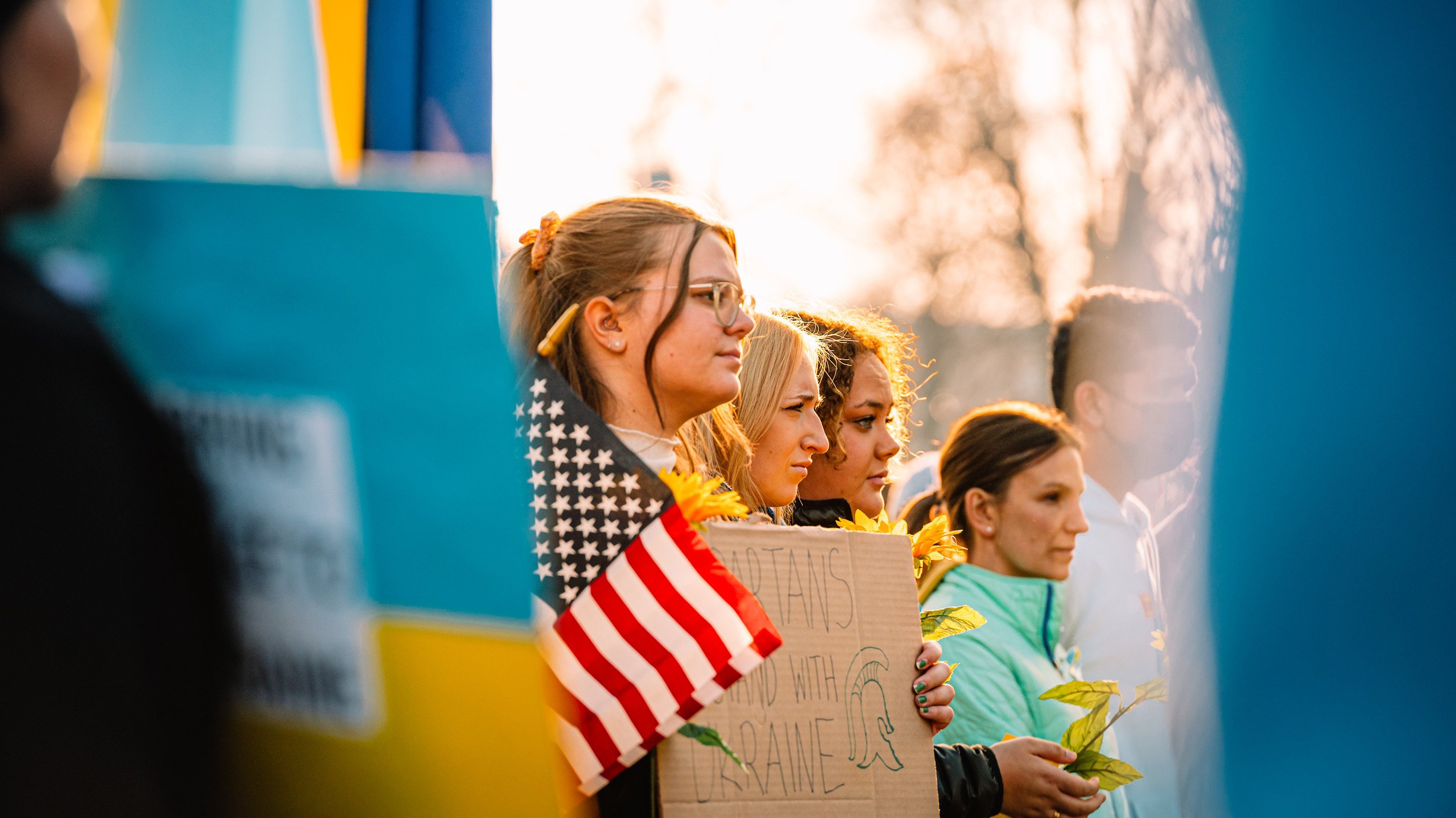 People at a rally for peace in Ukraine, holding signs and flags